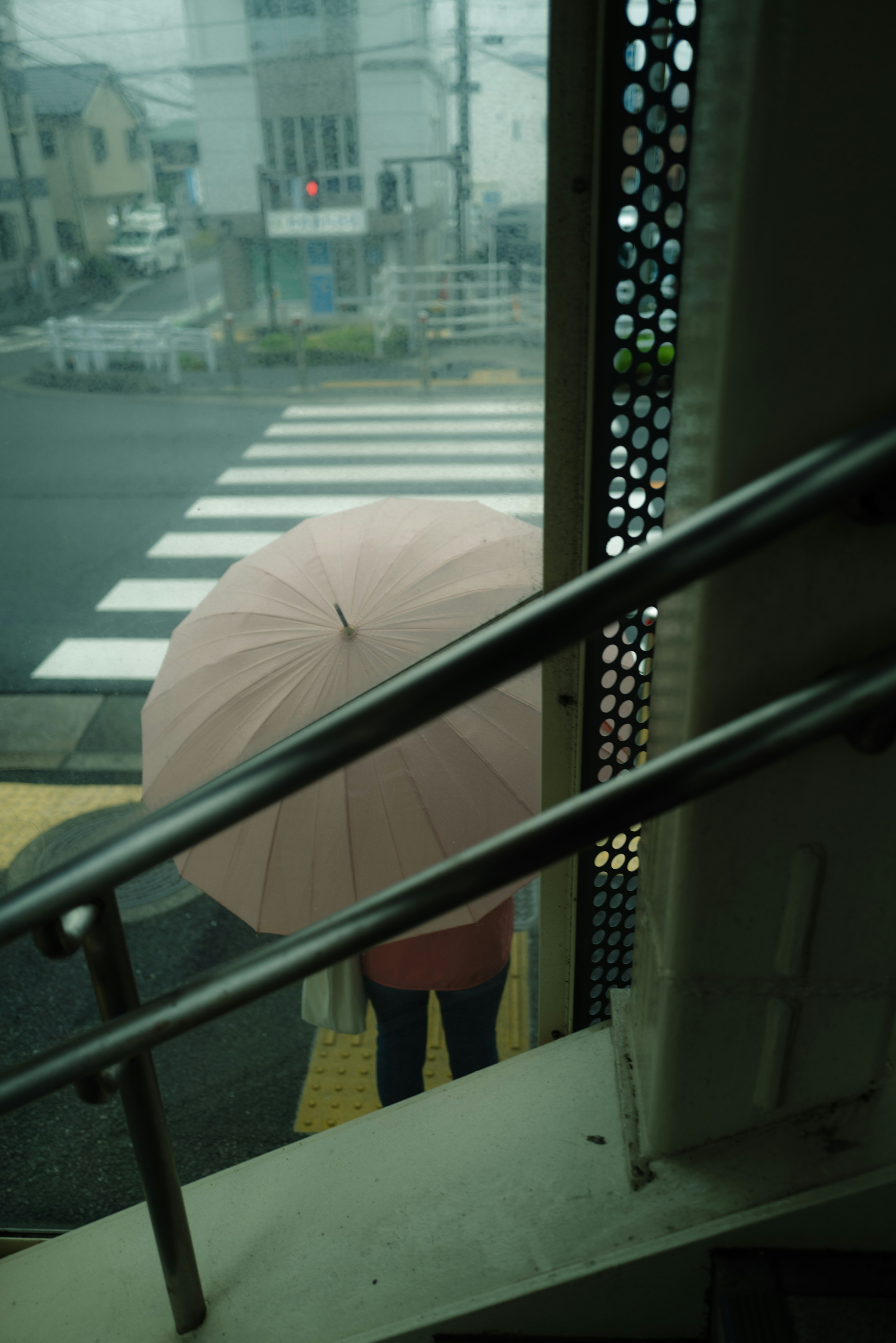 傘を持った人物が交差点の近くに立っている風景