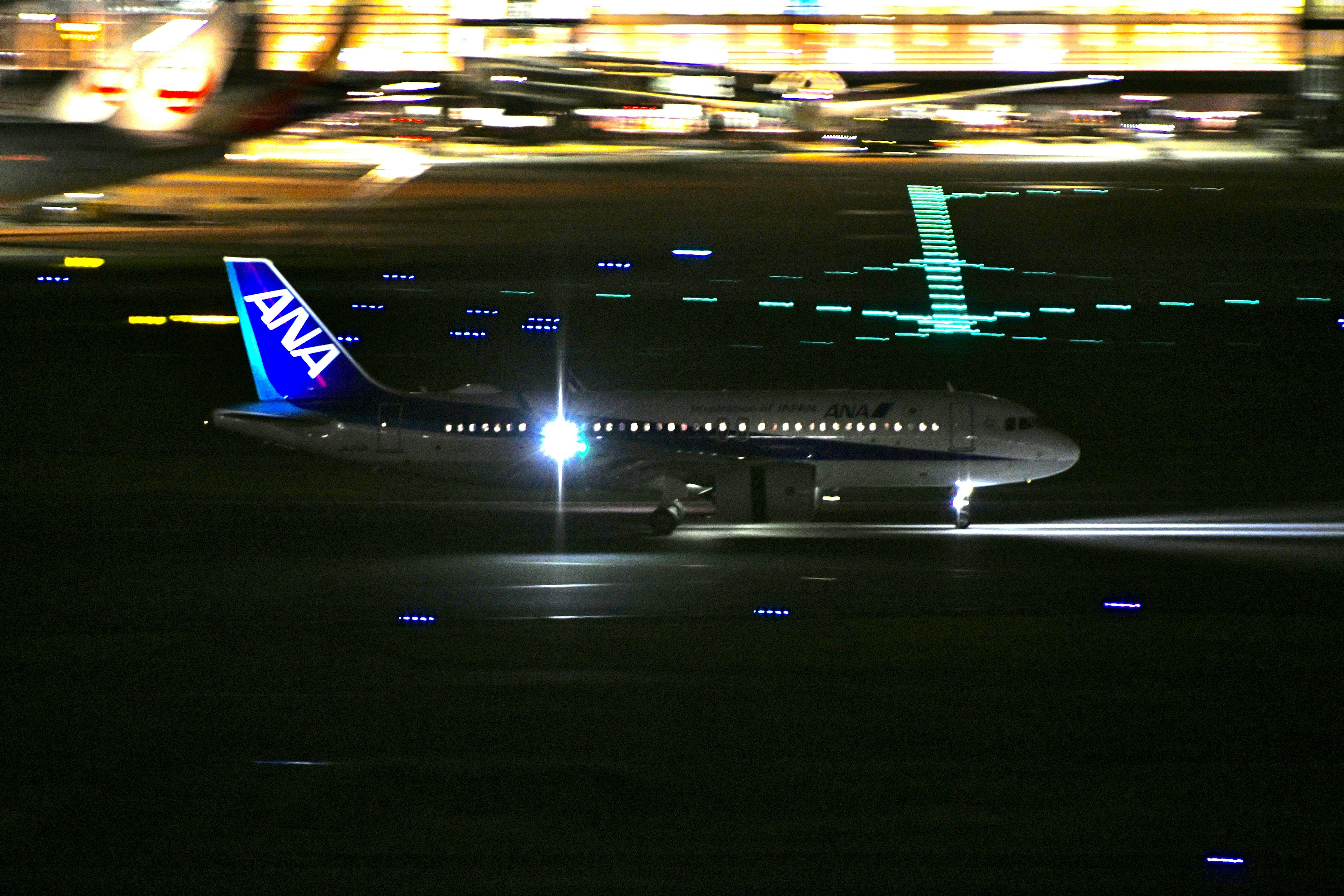 ANA airplane taxiing on the runway at night