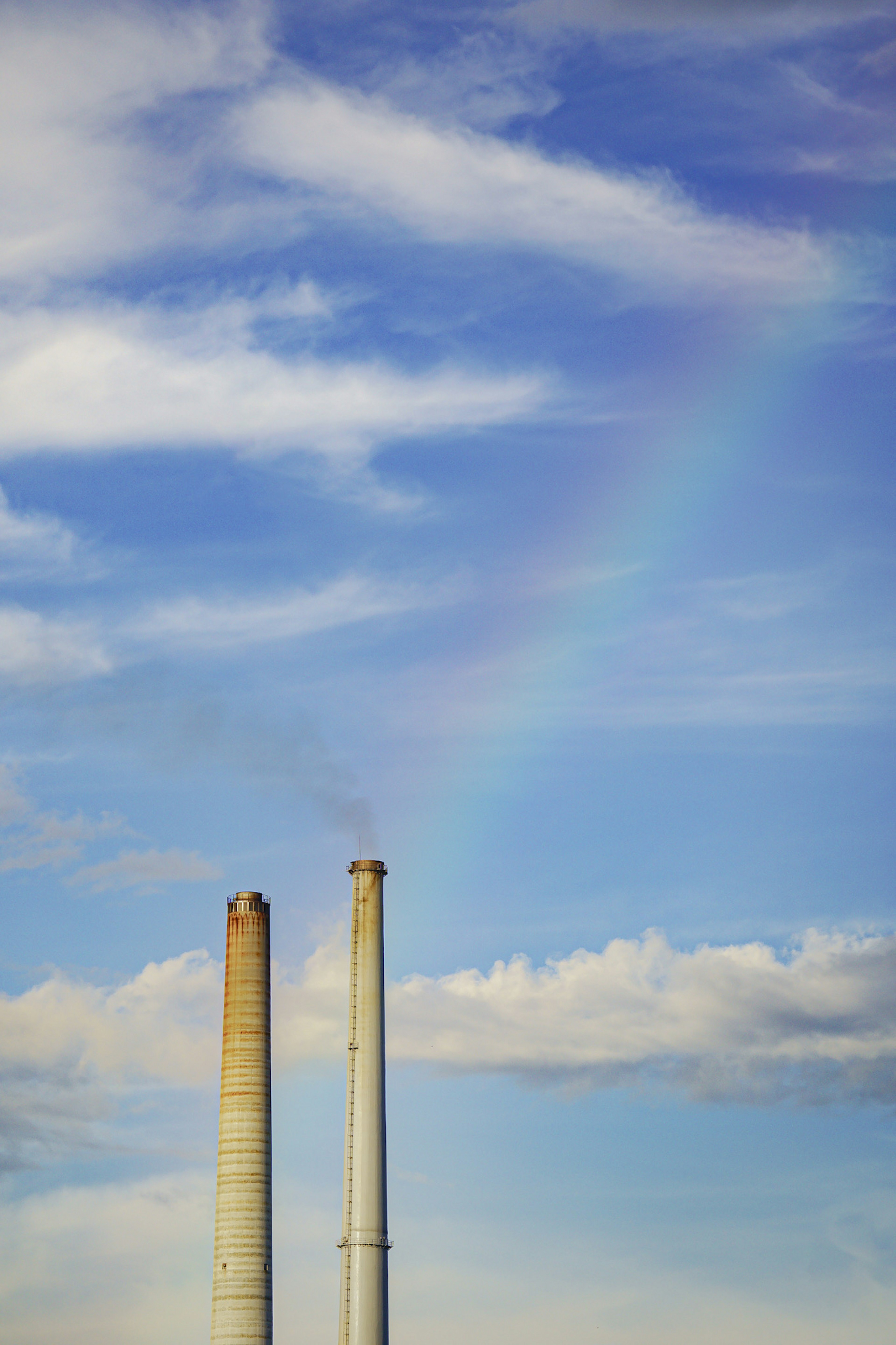 Cheminées contre un ciel bleu avec un arc-en-ciel