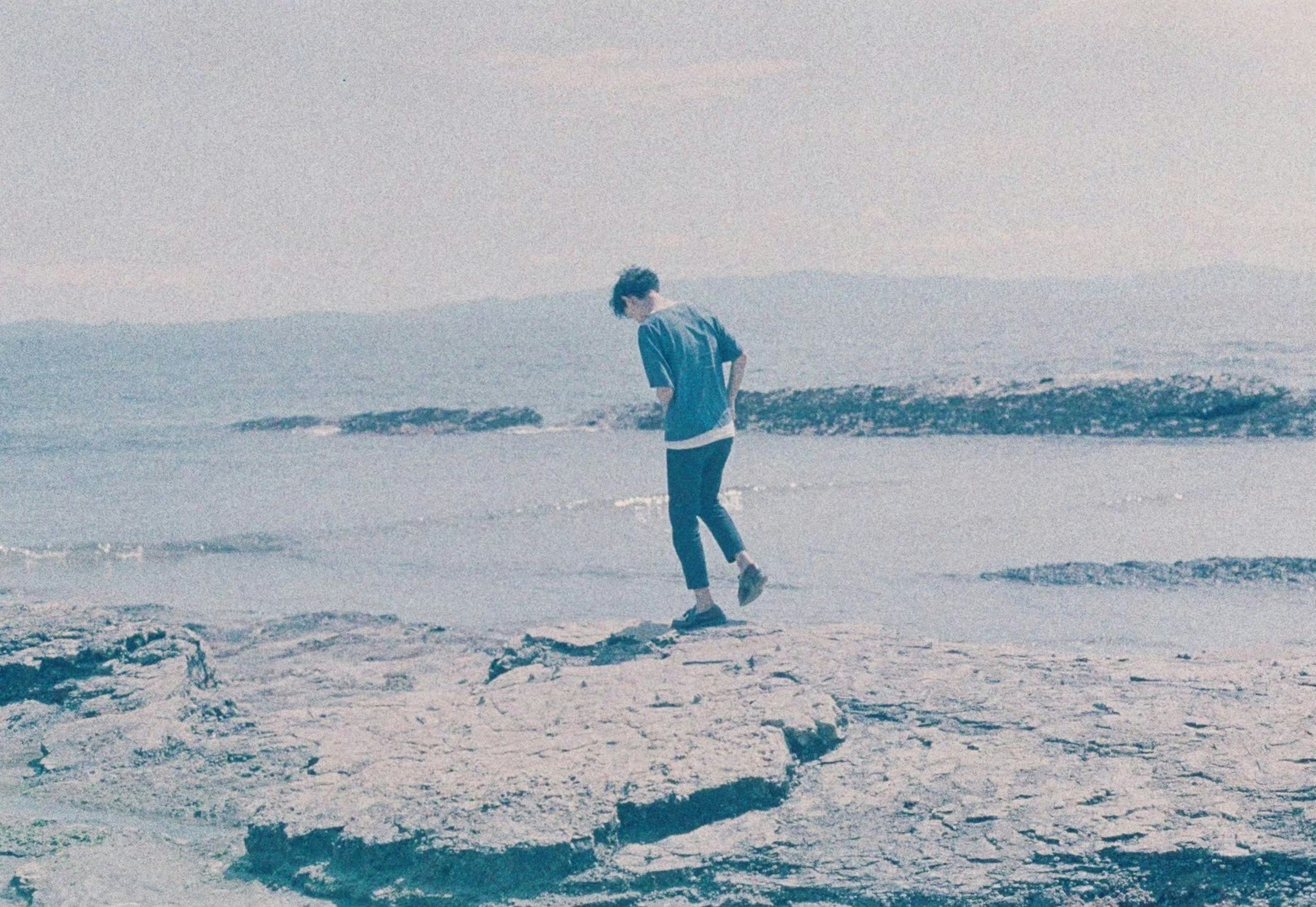 Eine Person, die auf Felsen an der Küste geht