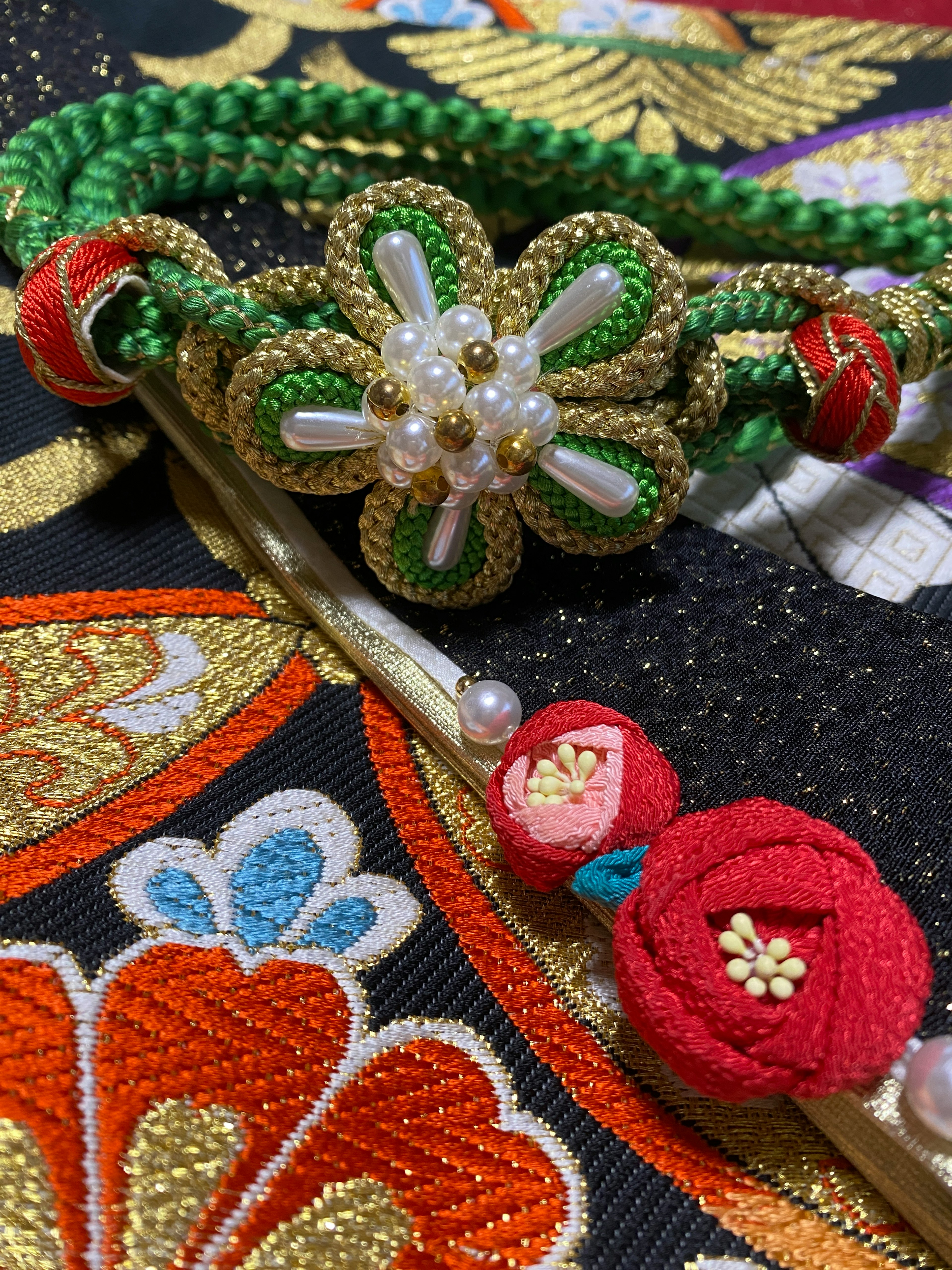 Accesorio tradicional japonés con cordón trenzado verde y decoración de flor blanca sobre tela bordada