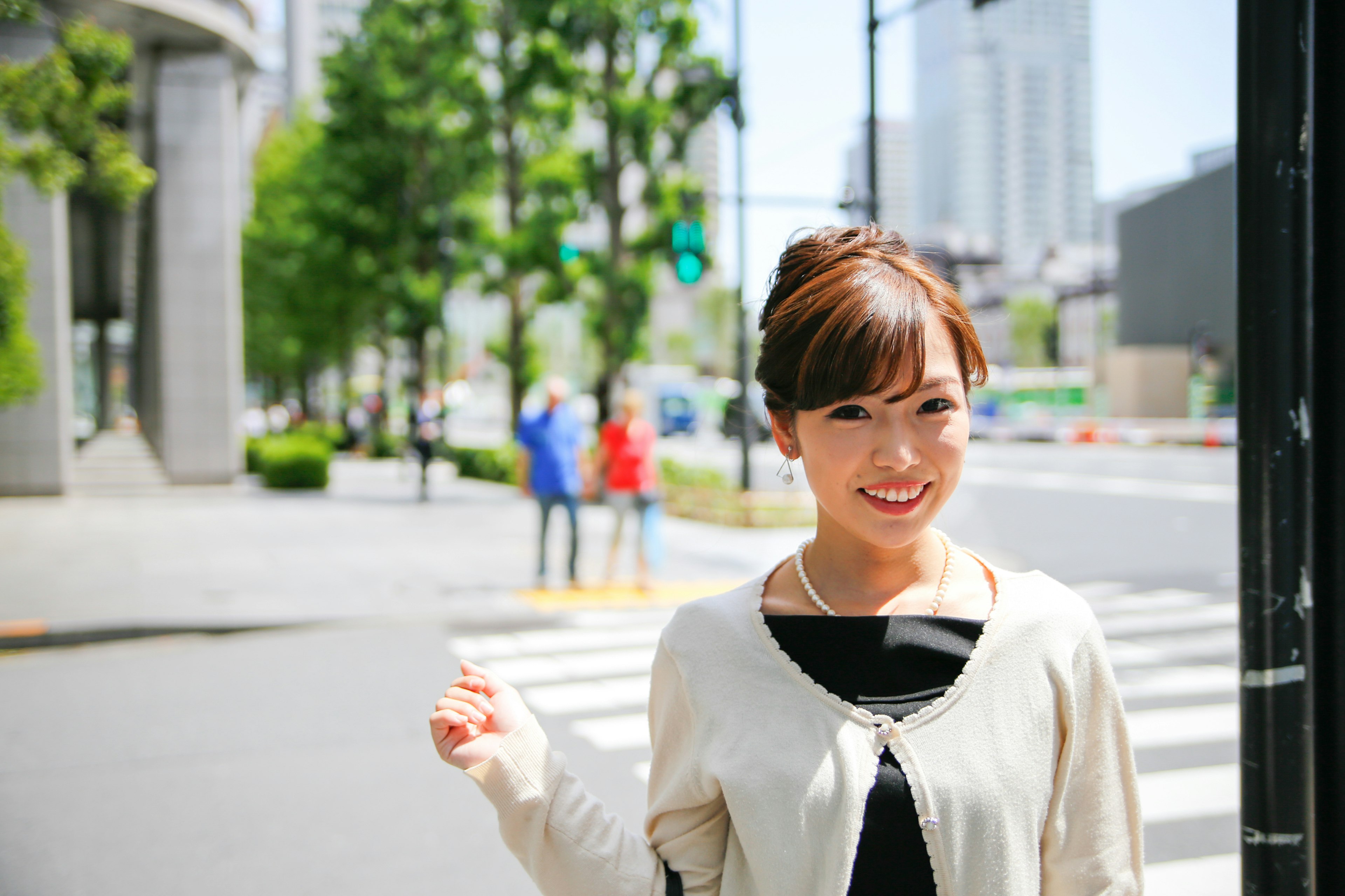 街角に立つ女性の笑顔と背景の都会の風景