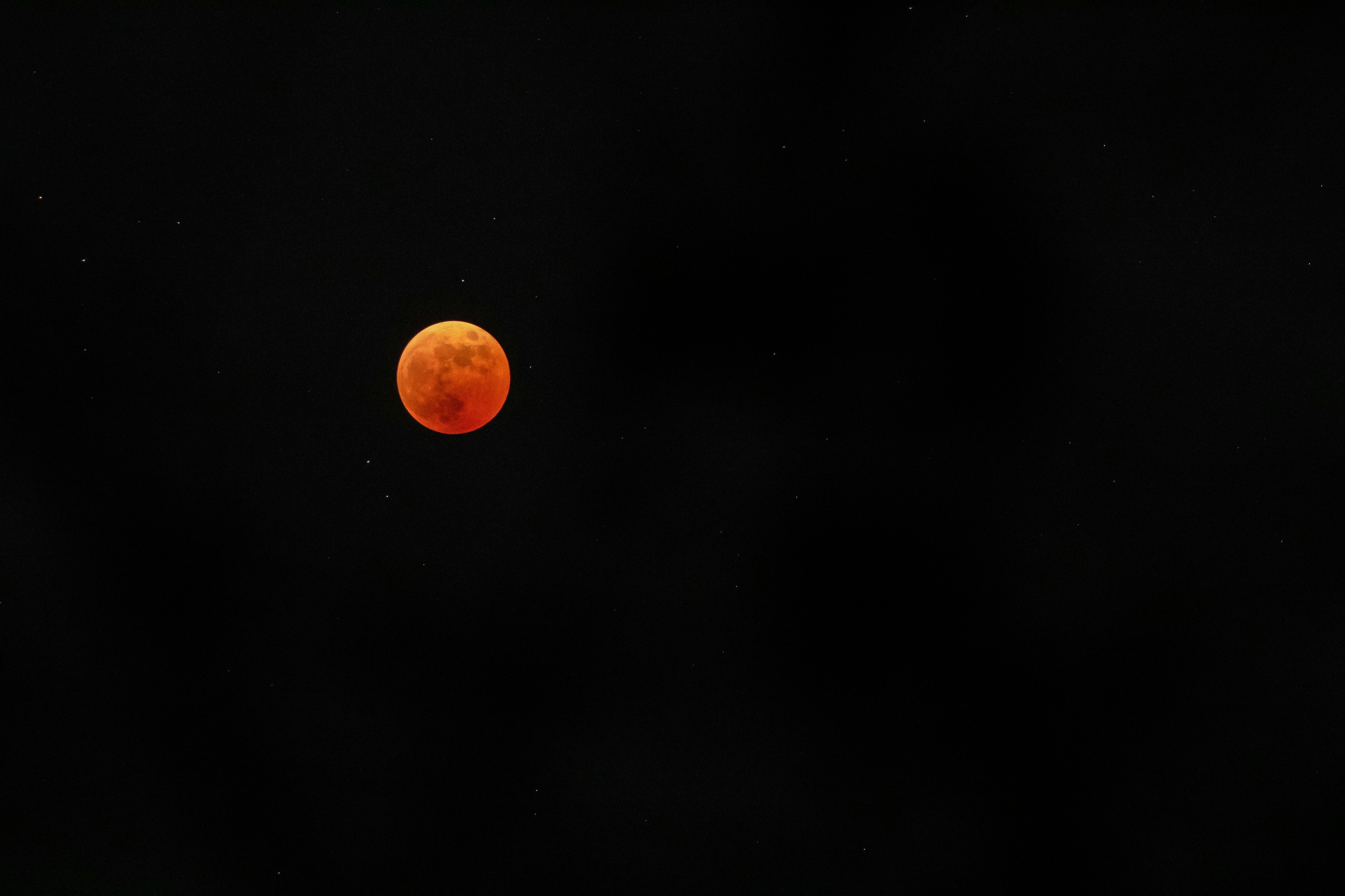 Red full moon floating in a dark sky