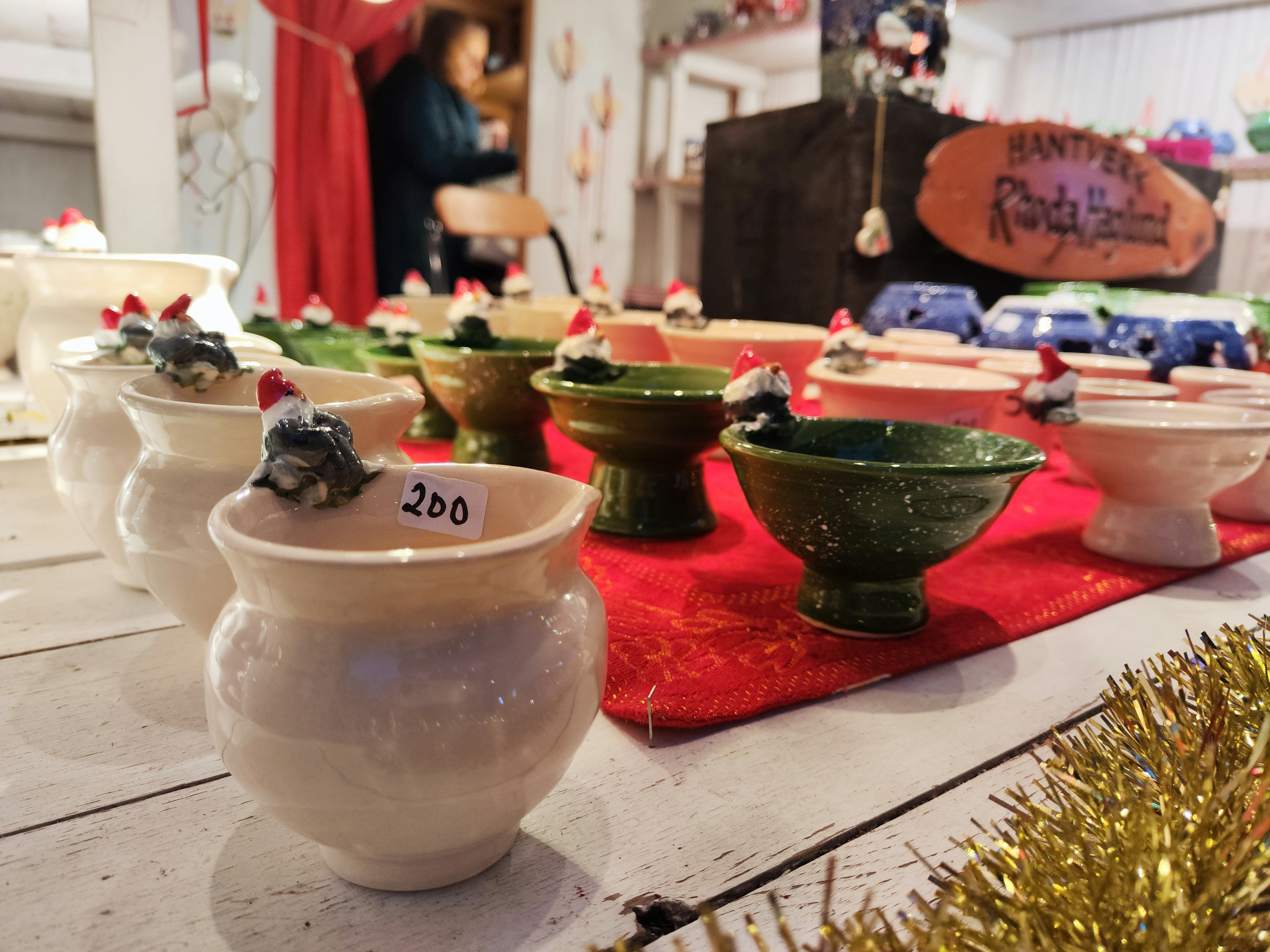 Display of ceramic bowls with Santa hat decorations in a festive market setting