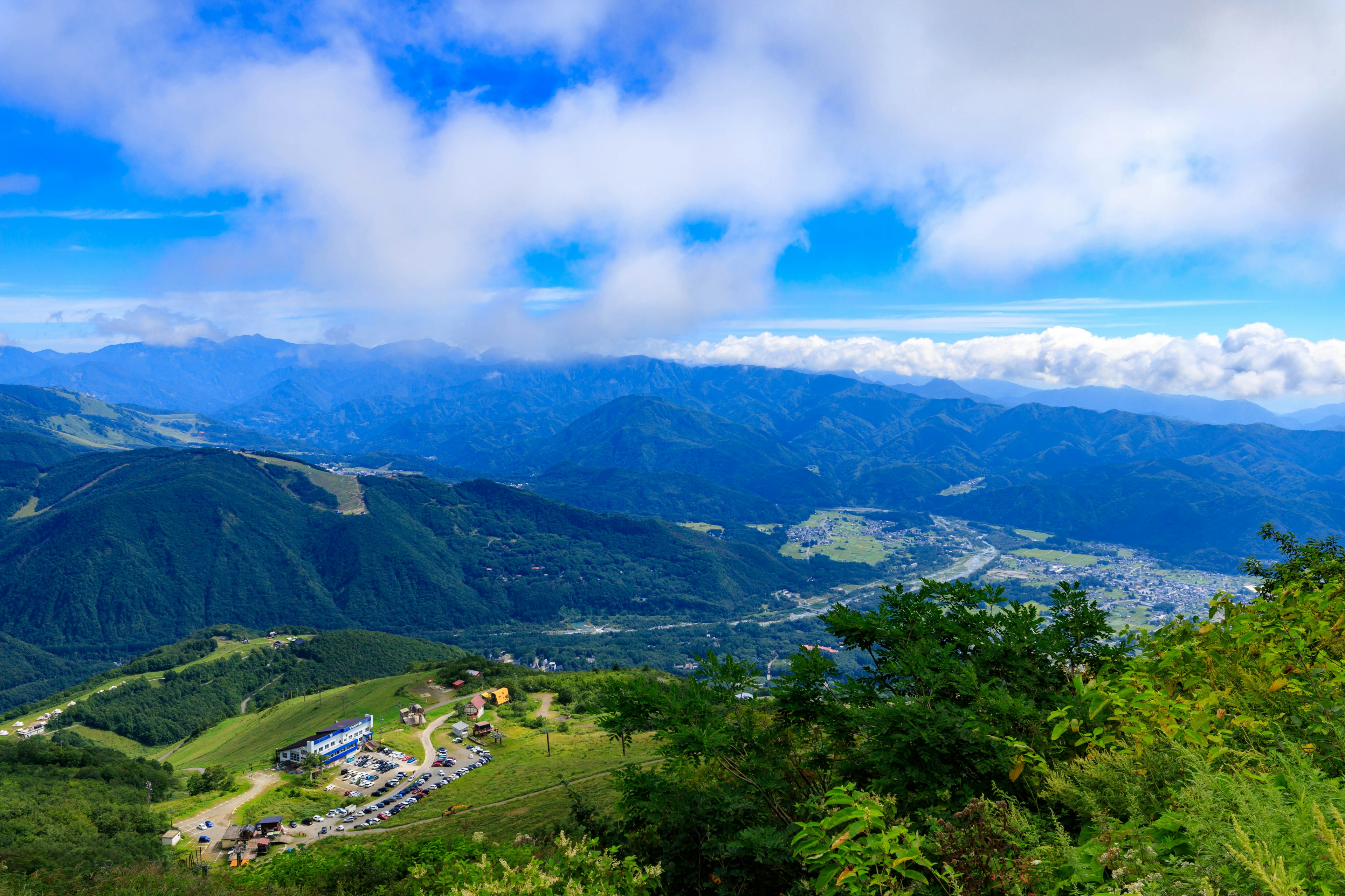 蓝天和云彩下的山脉全景 绿色山丘和城镇风景