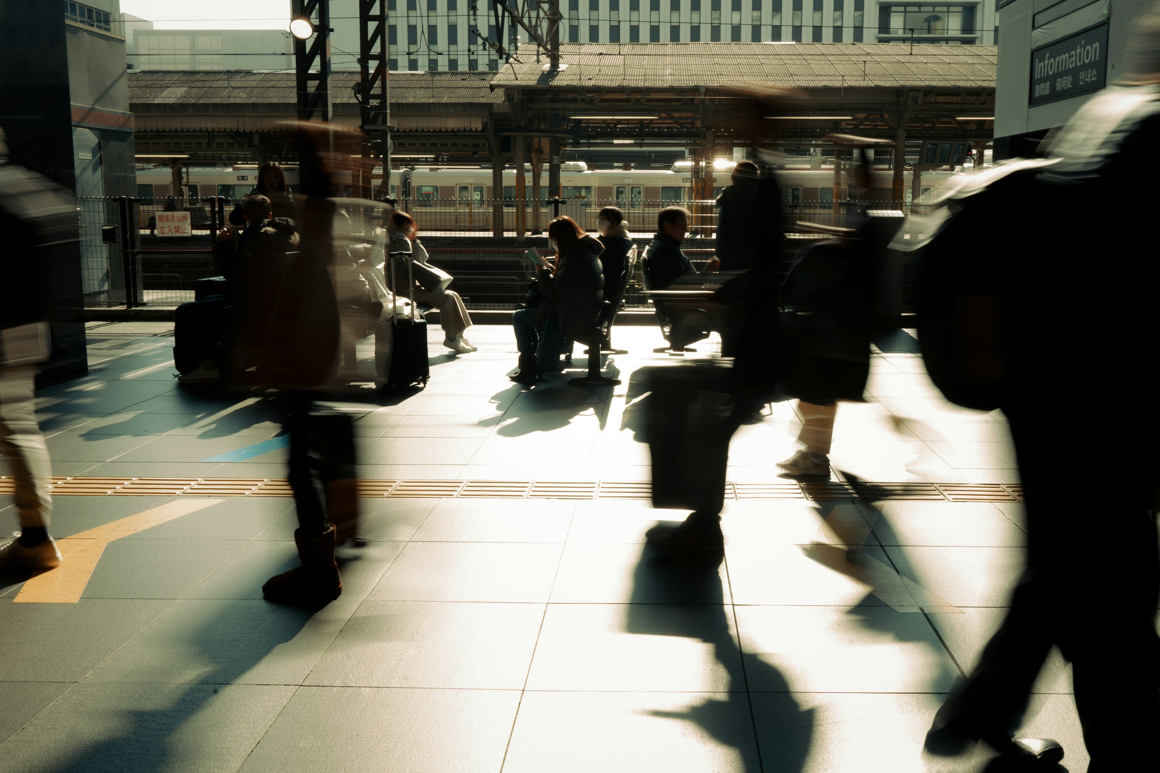 A bustling train station scene with people moving and carrying luggage