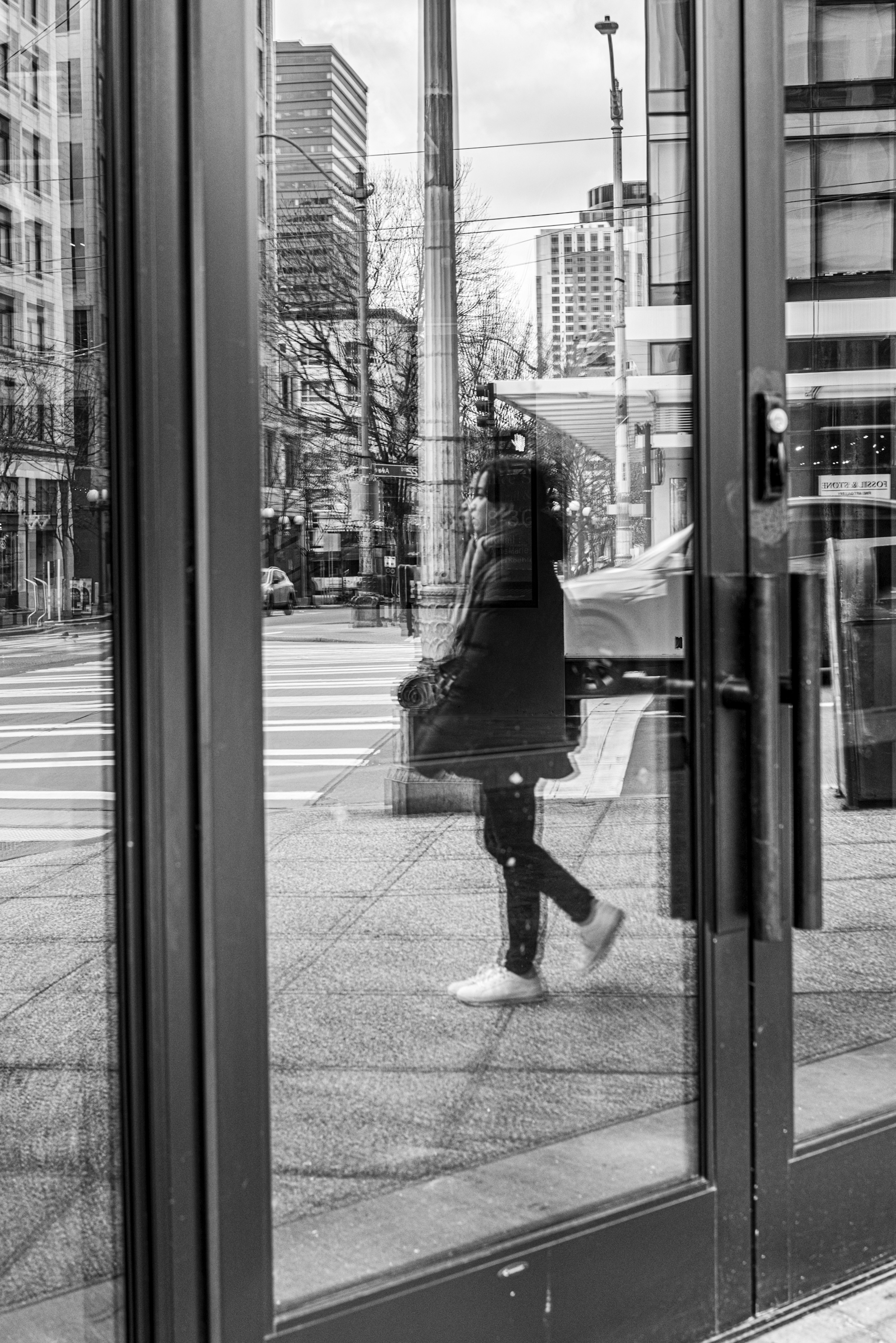 Silhouette di una persona riflessa in porte di vetro con uno sfondo urbano