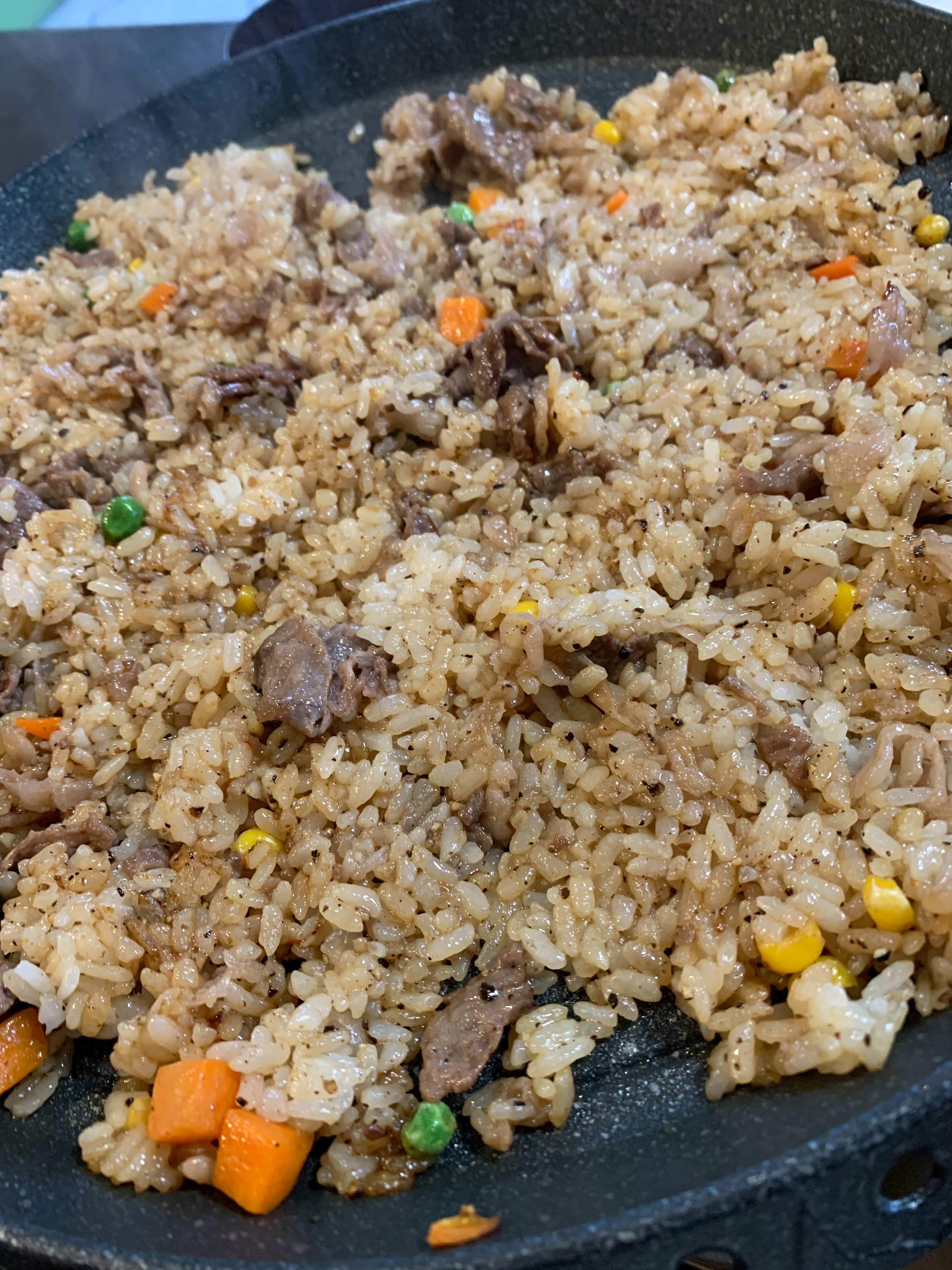 Arroz frito mezclado con carne y verduras en un plato