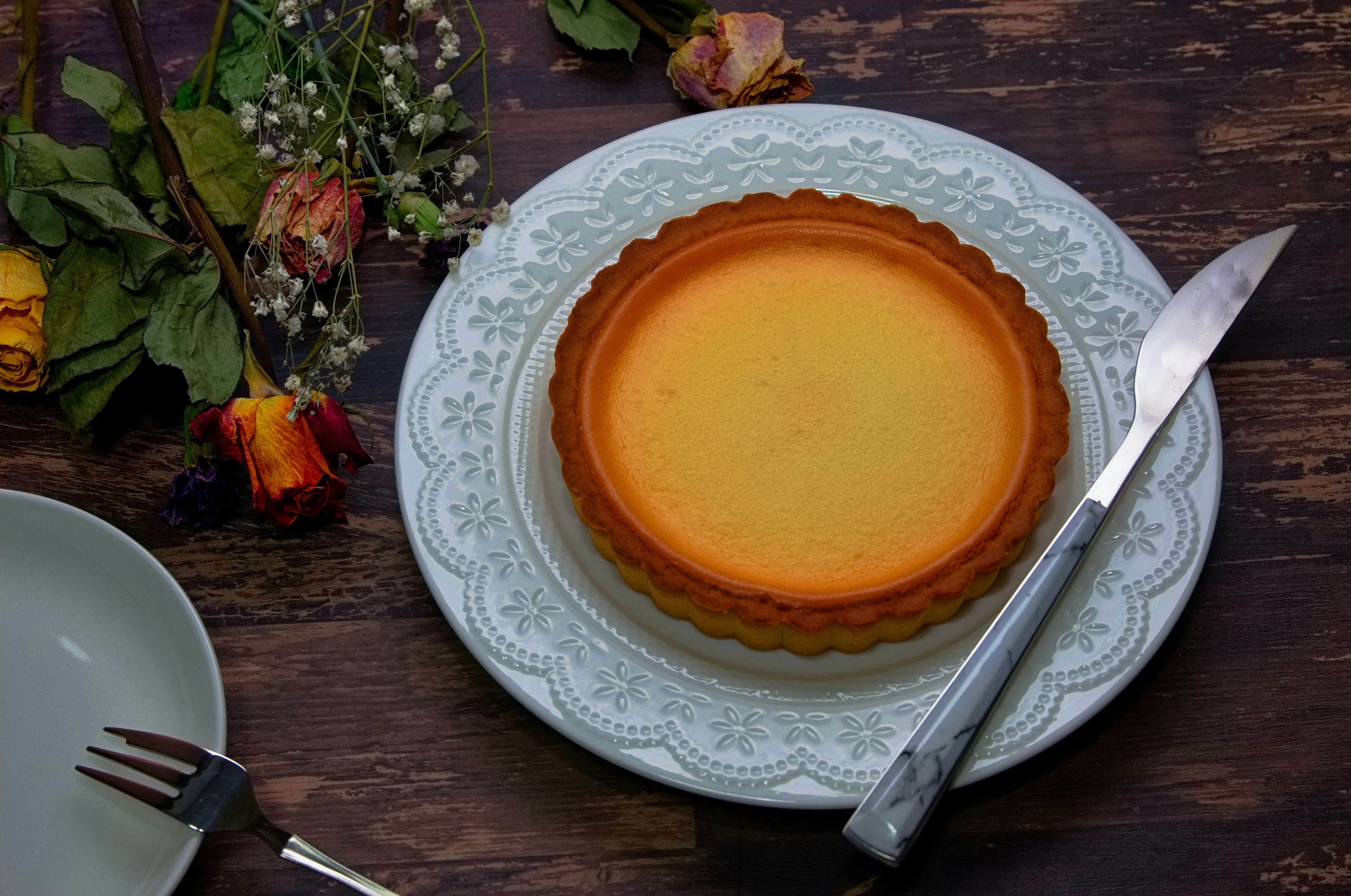 A beautiful tart on a blue plate with a knife beside it