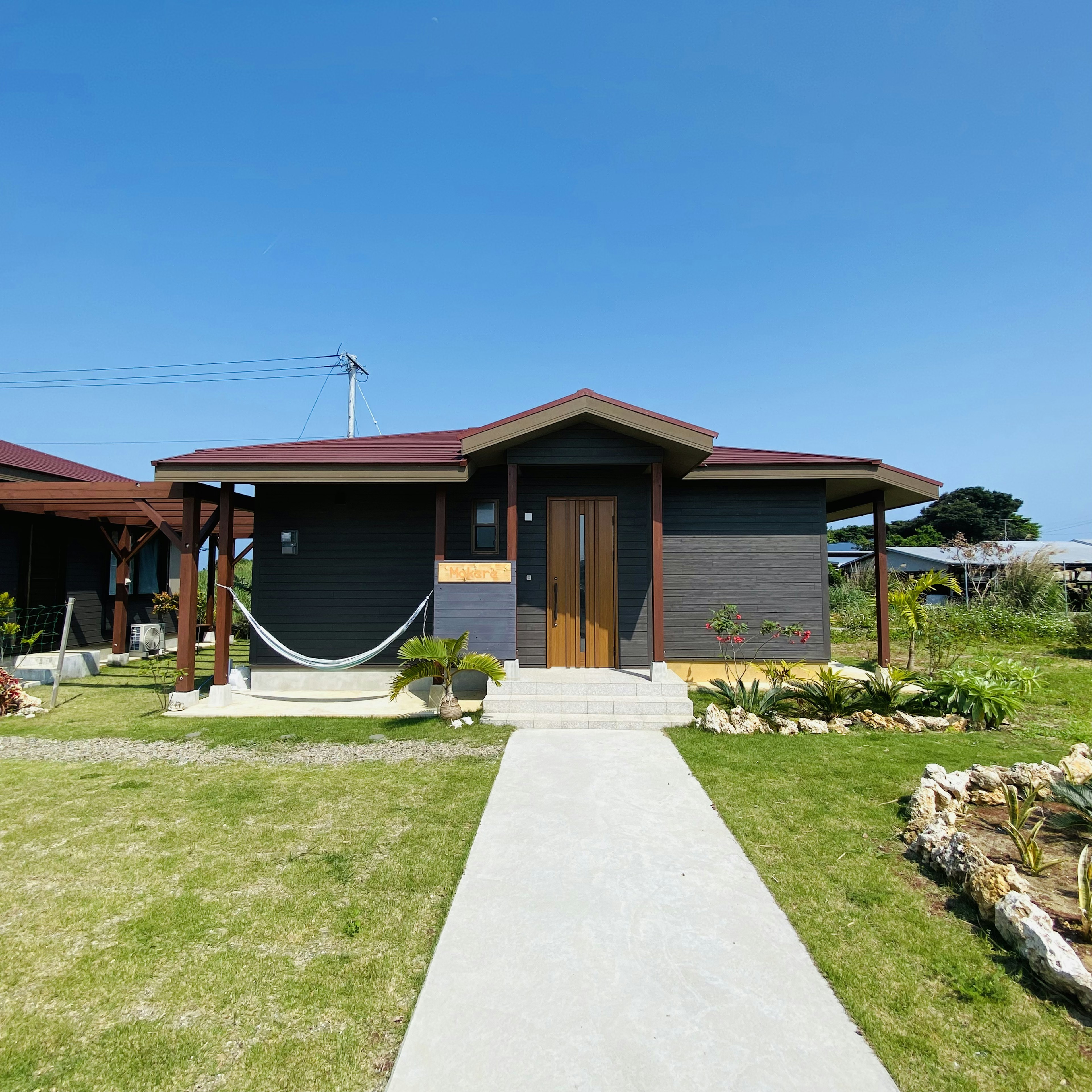 Rumah keluarga modern di bawah langit biru dengan taman hijau