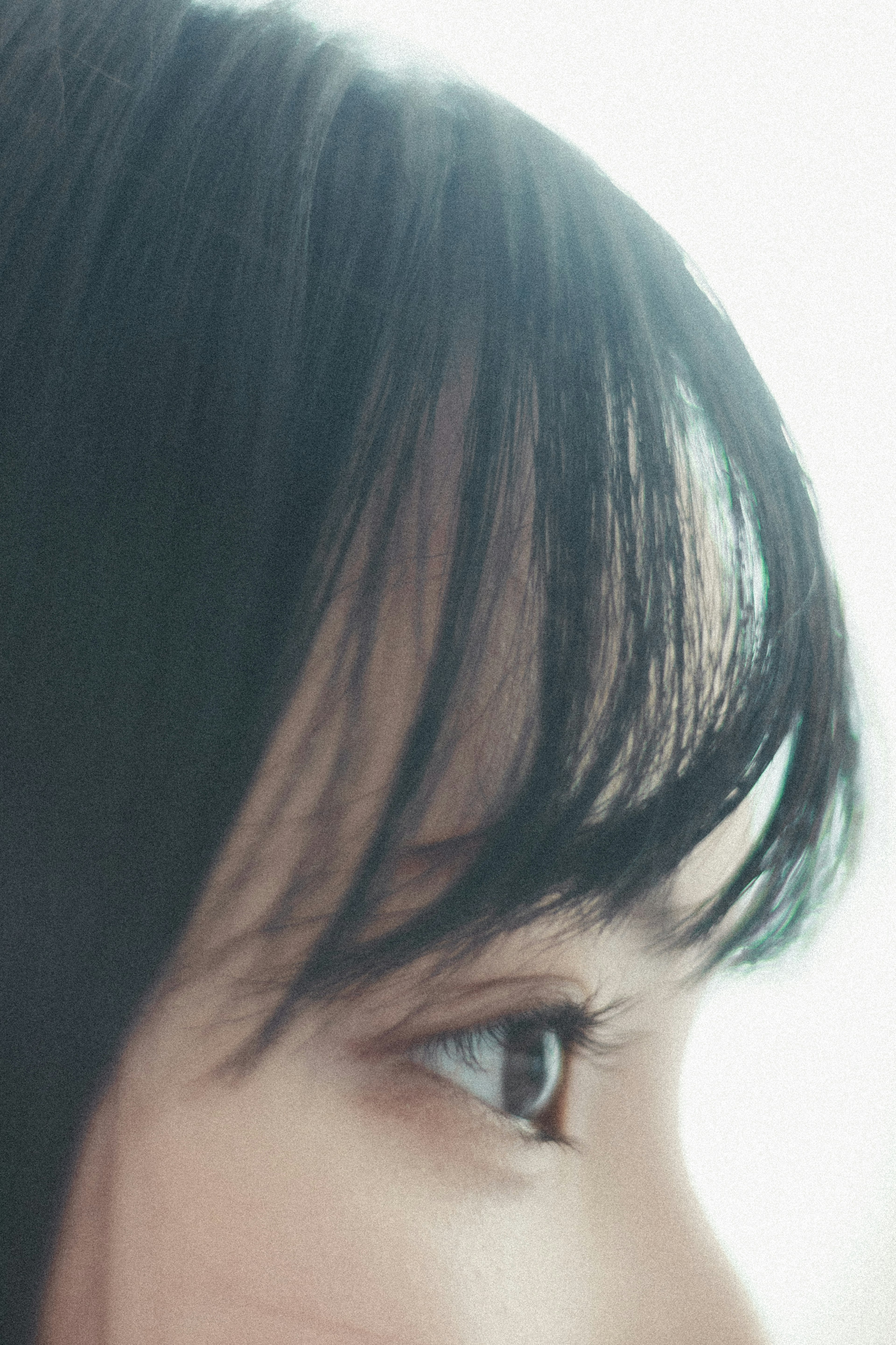 Close-up of a woman's profile featuring soft hair and eye against a bright background