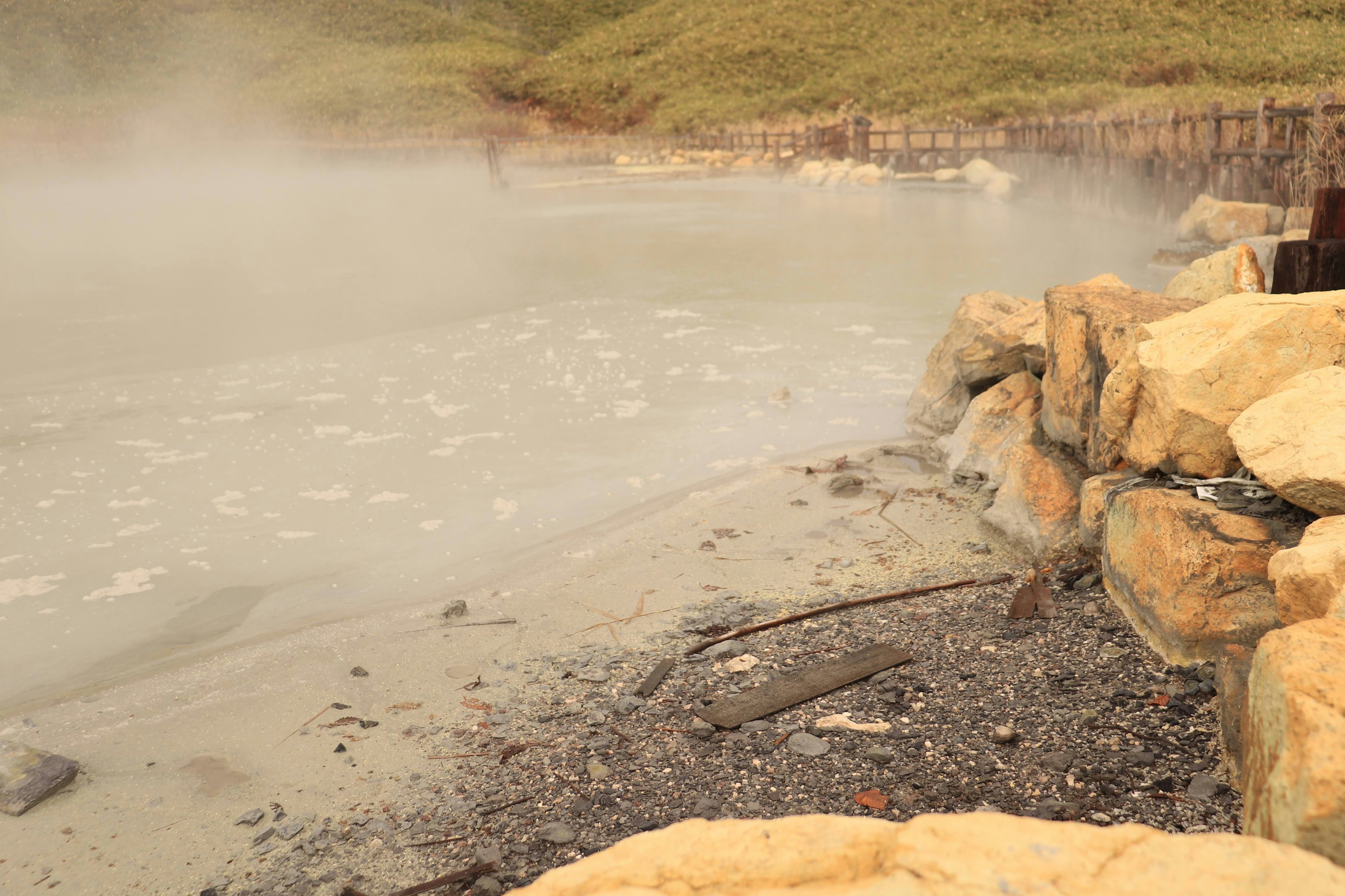 Felsige Küste einer heißen Quelle mit Nebel und Wasser