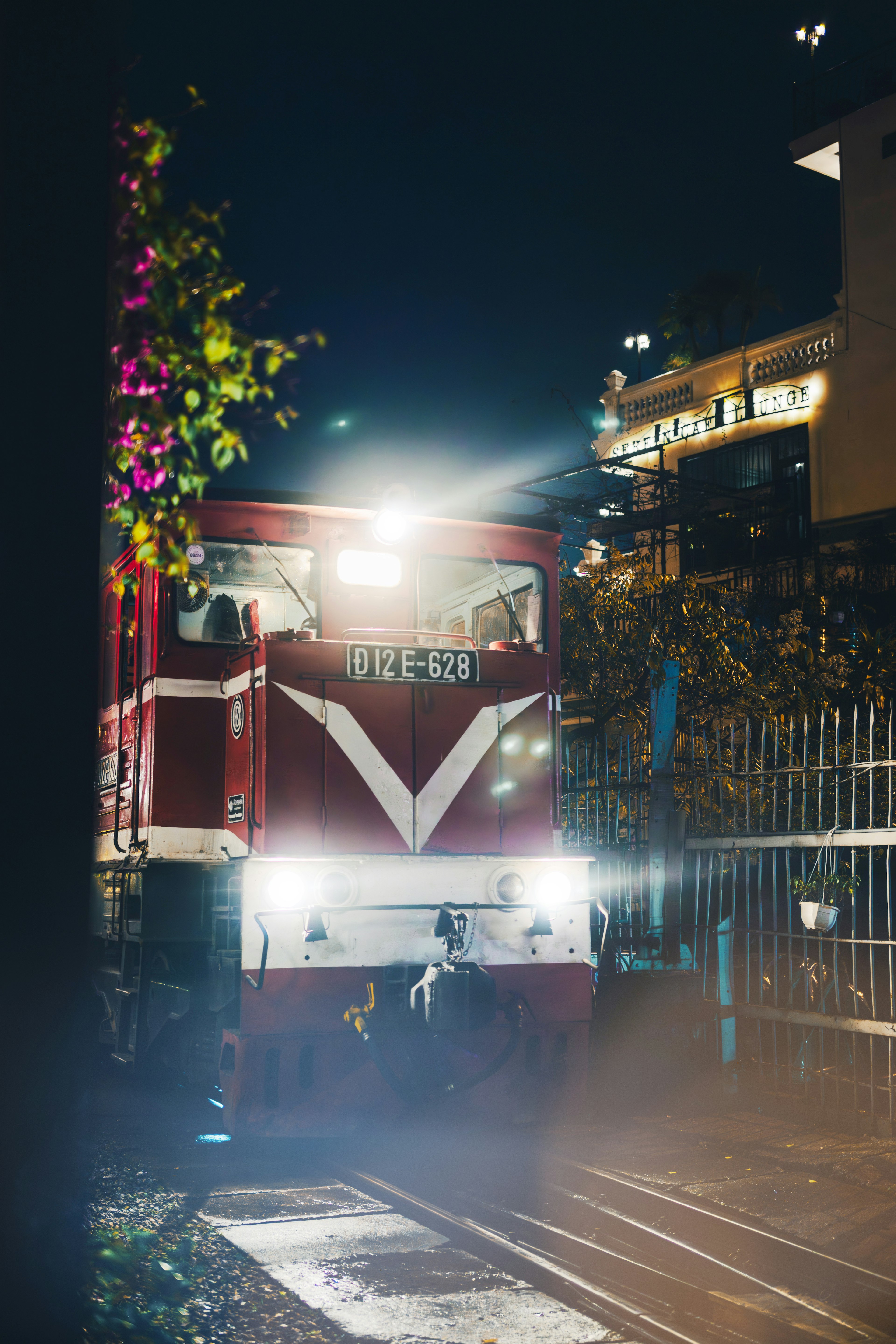 Lokomotif merah di stasiun malam dengan lampu depan yang cerah