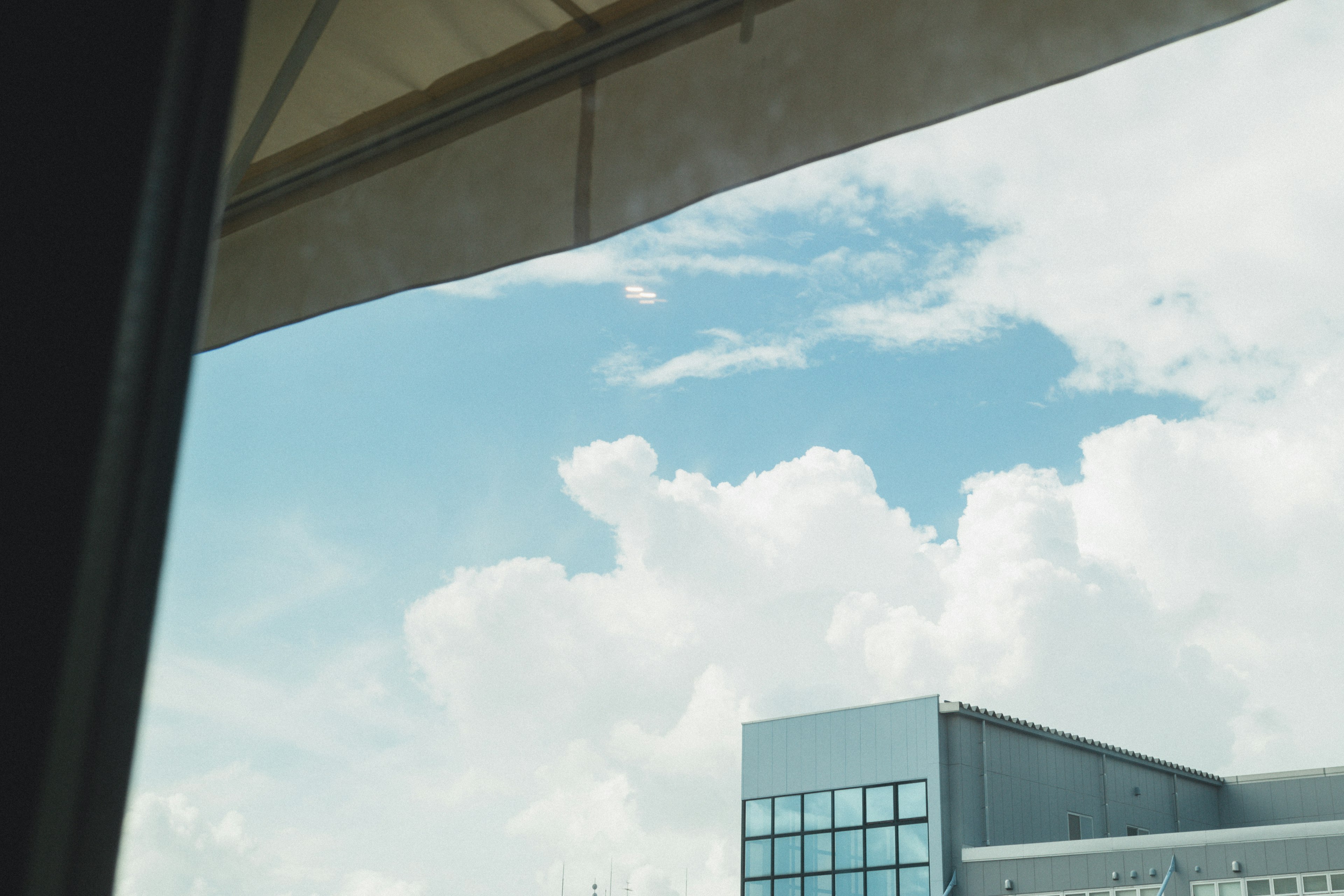 View of blue sky with fluffy white clouds and a building in the foreground