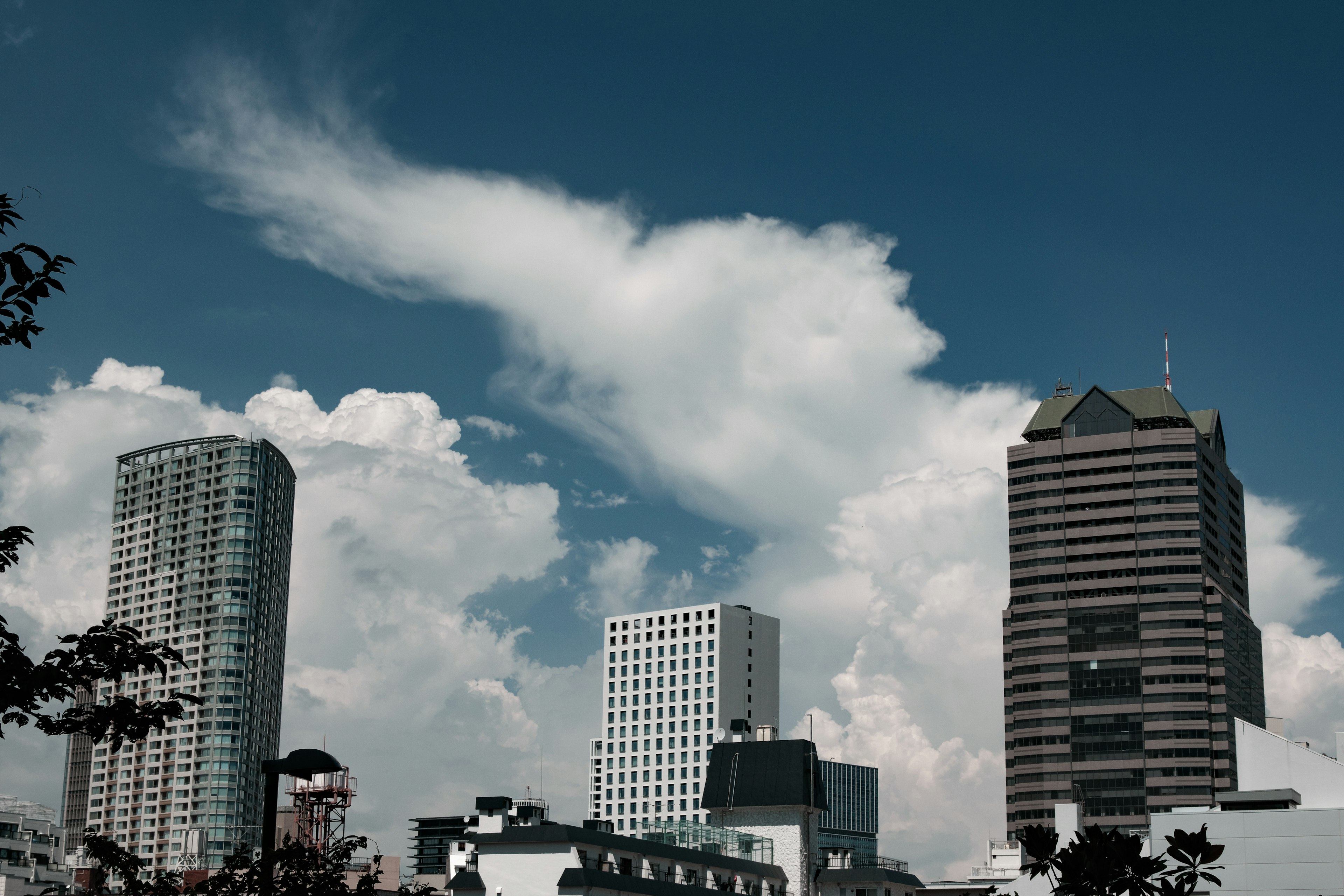 Pemandangan kota dengan gedung tinggi di bawah langit biru dan awan