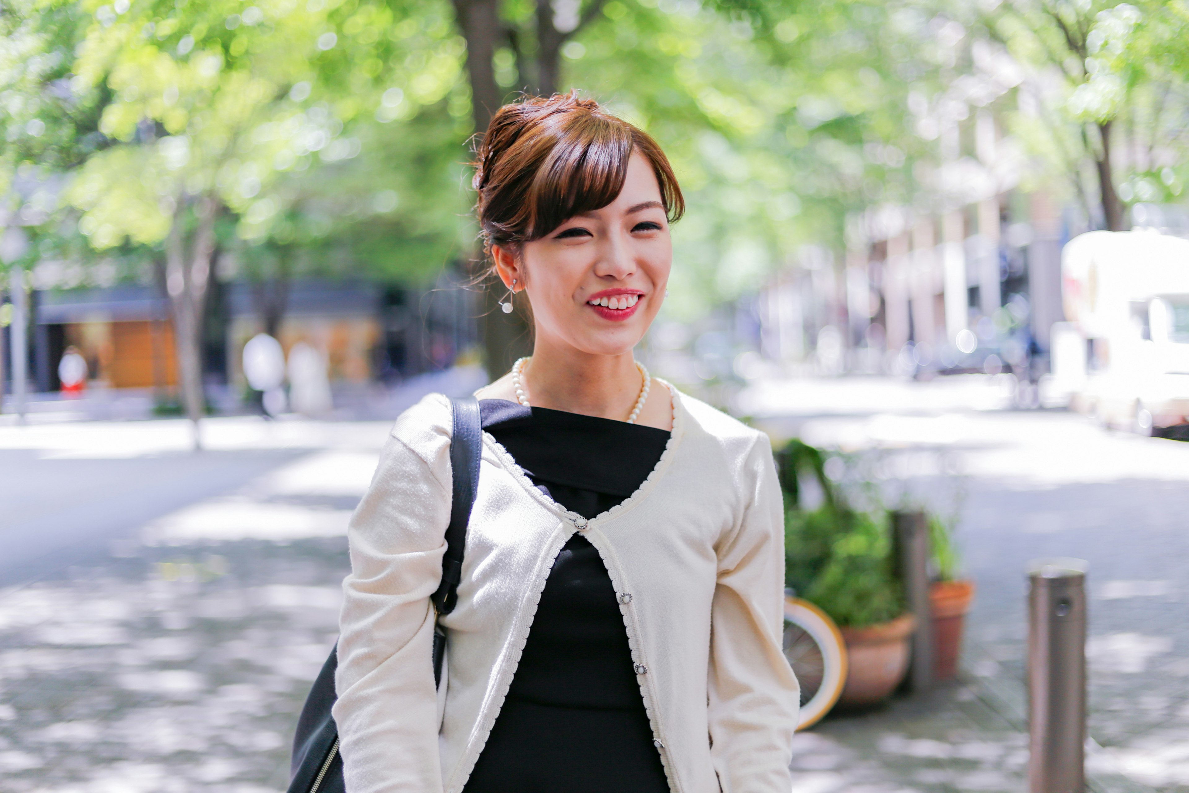 Smiling woman in a city street with green trees in the background