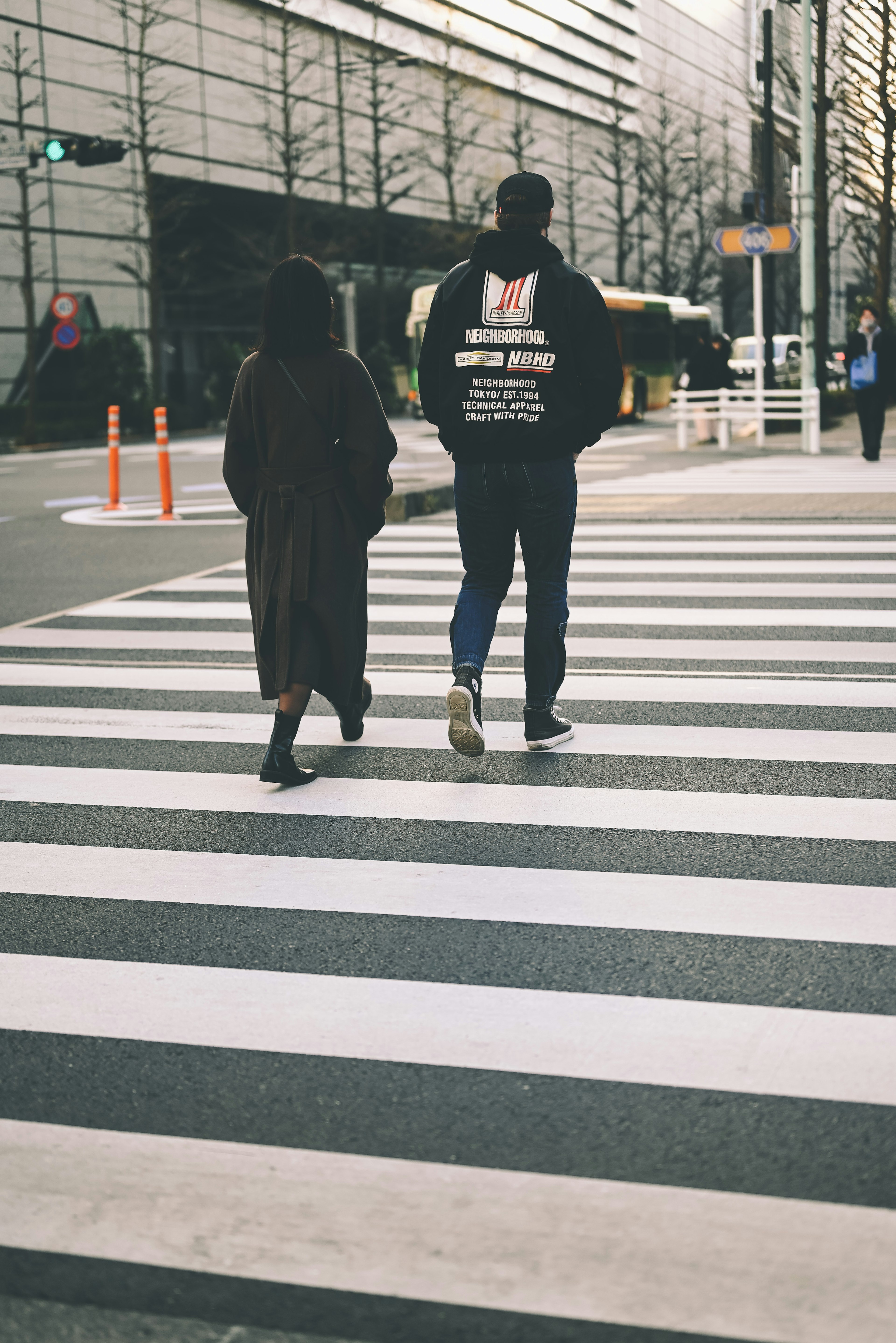 横断歩道を渡る二人の人物と現代的な建物