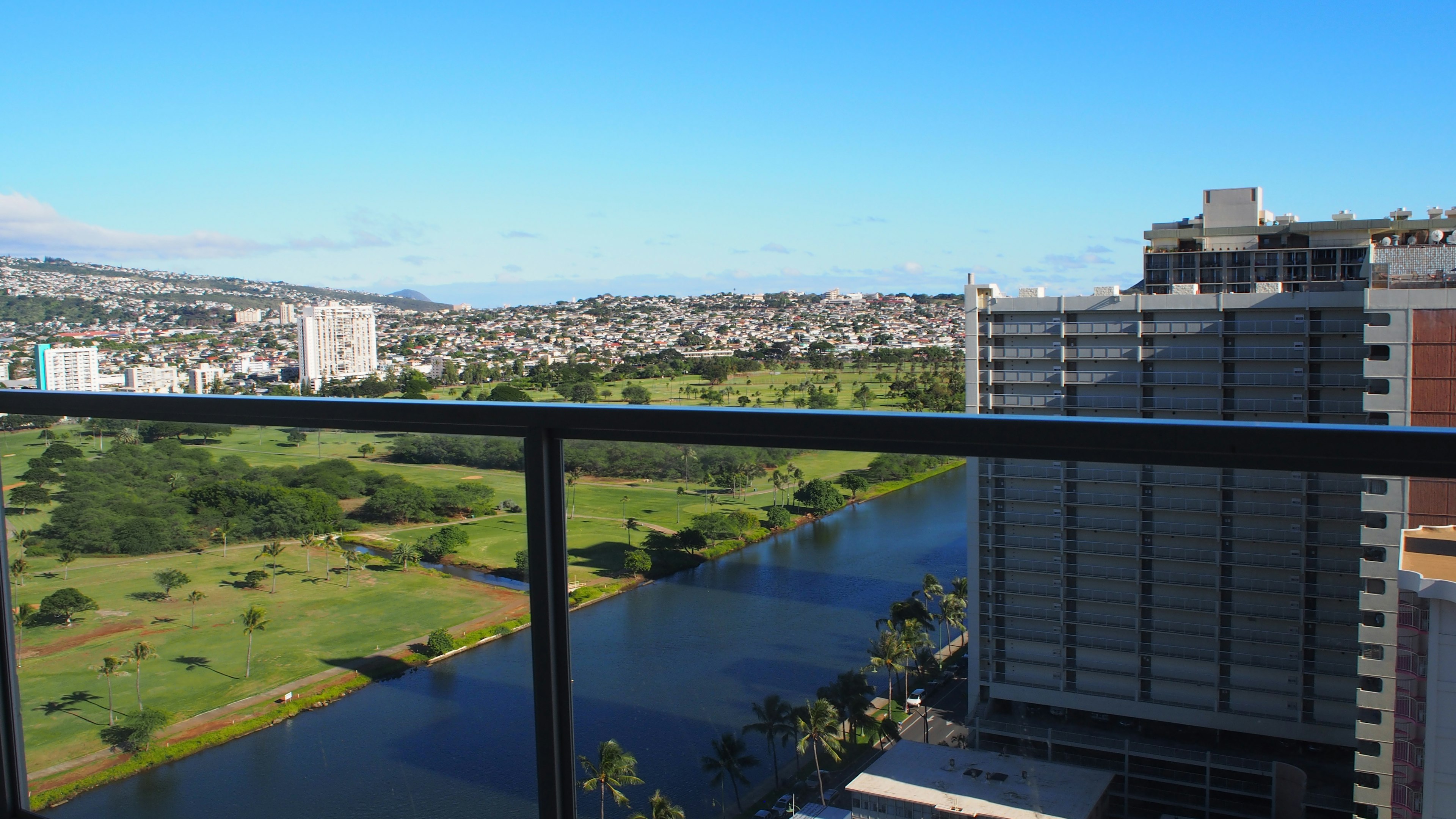 View from a high-rise balcony showcasing green parkland and a river