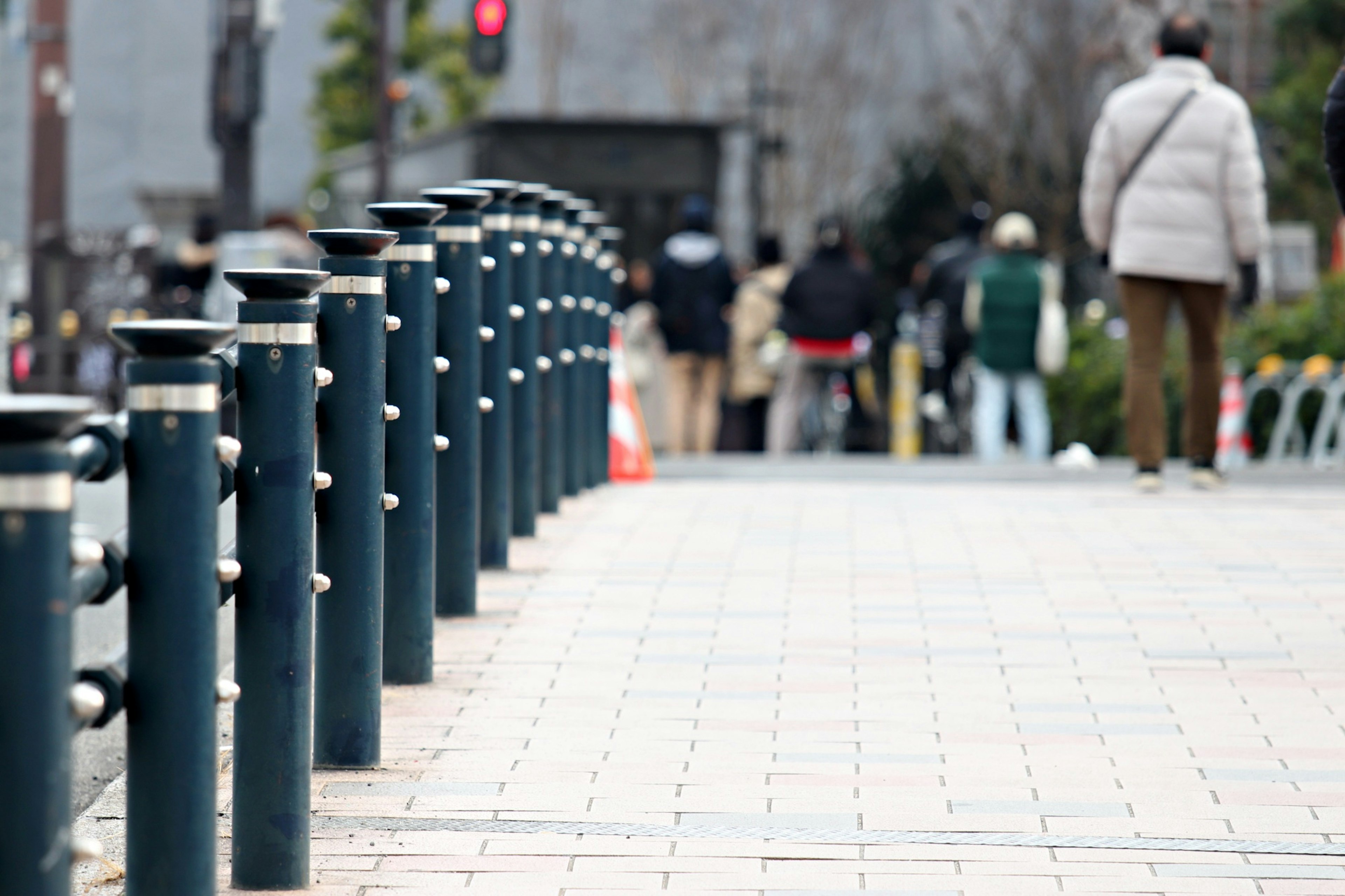 Rangée de bollards bleus le long d'un trottoir avec des gens en arrière-plan