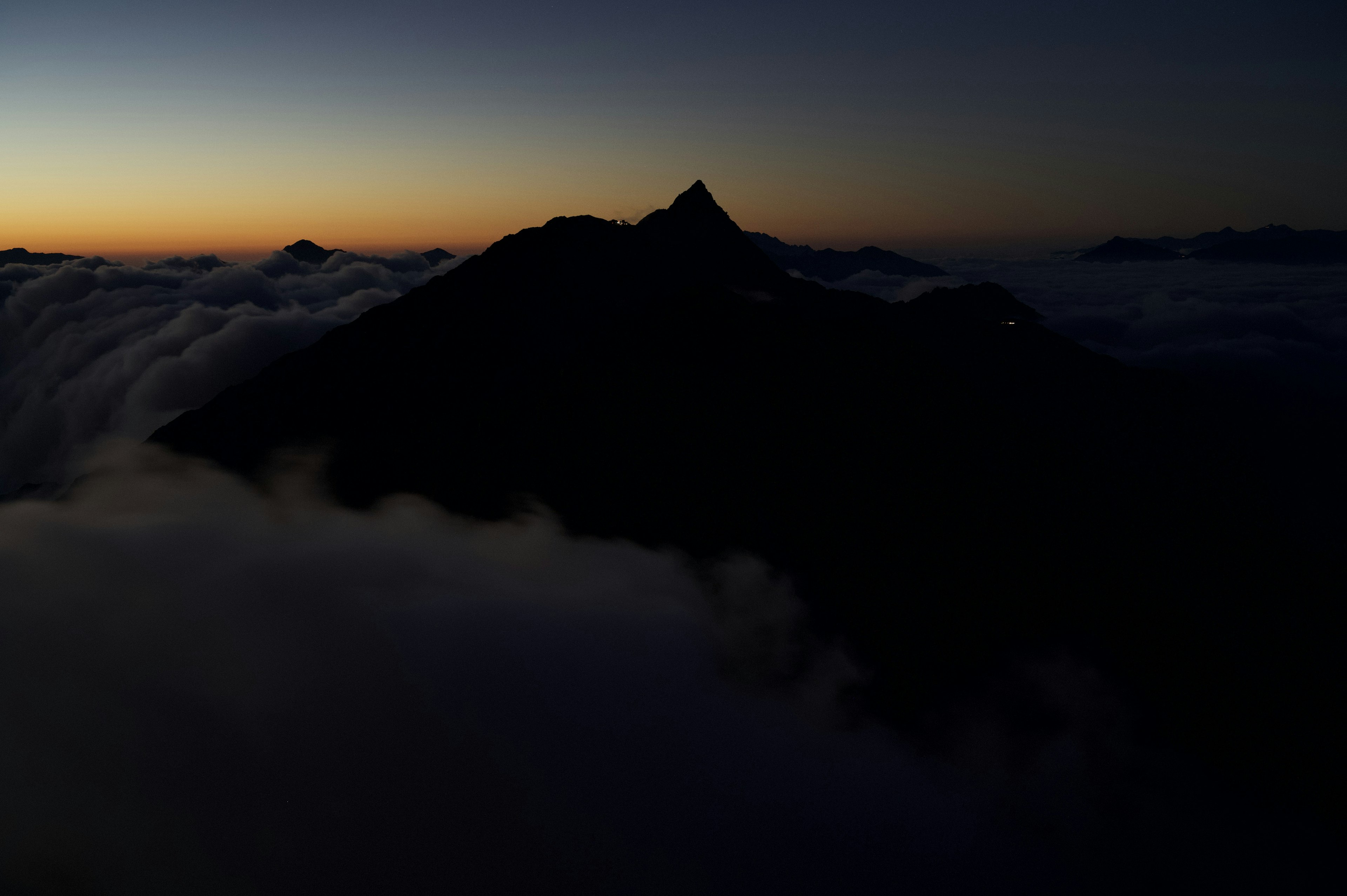 Silueta de una montaña sobre las nubes al atardecer