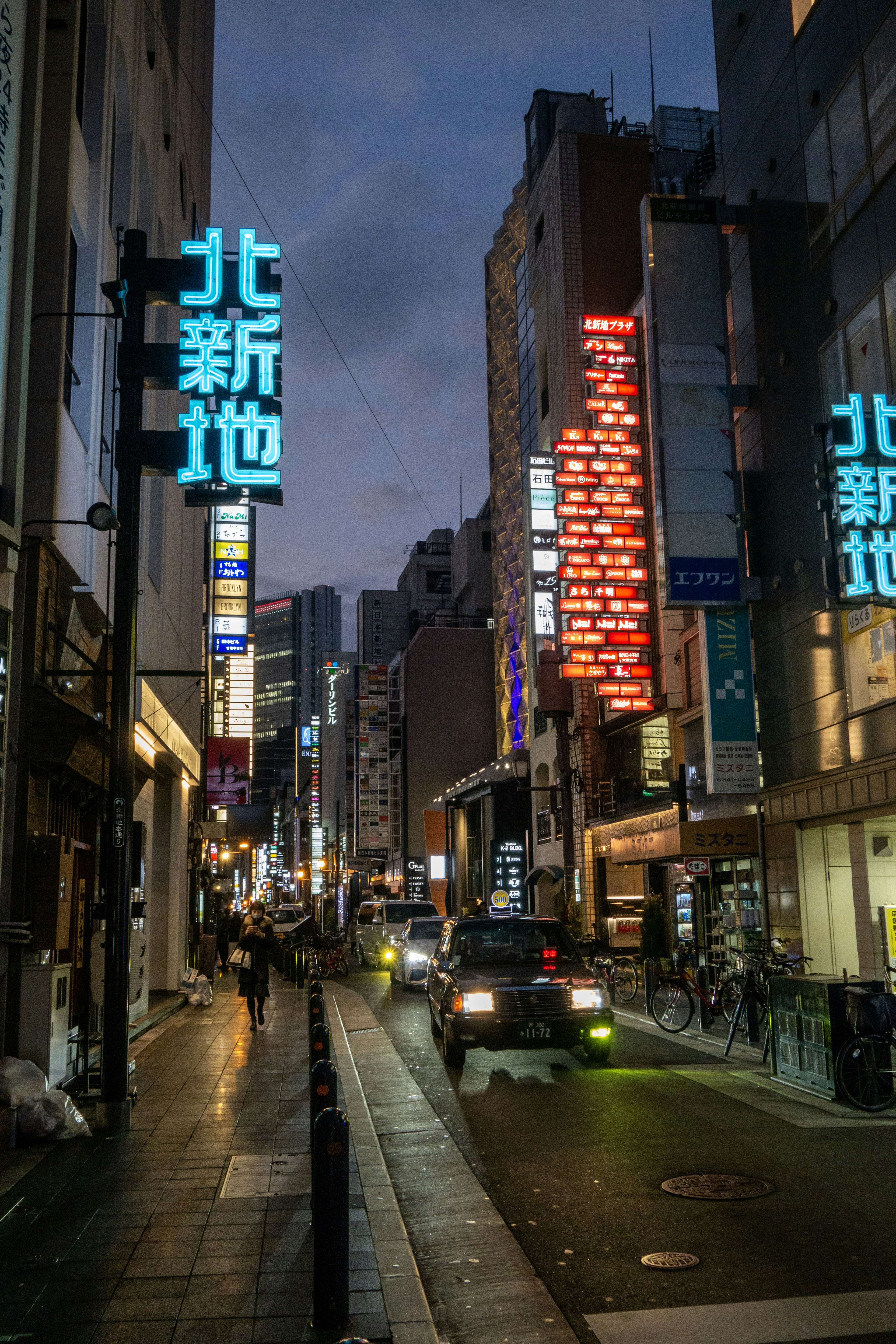 Escena nocturna en una calle de Shinjuku con letreros de neón brillantes