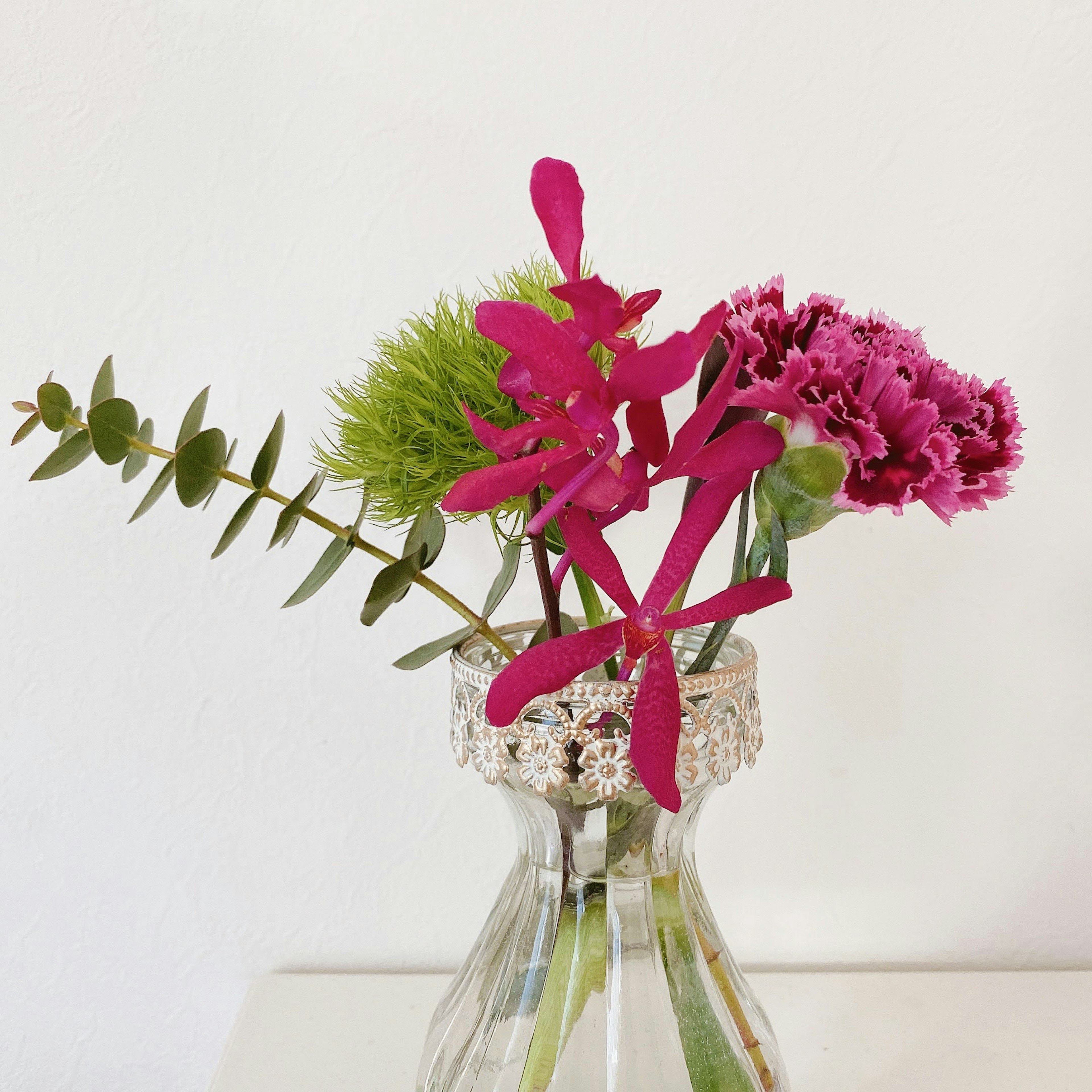 A clear vase filled with vibrant flowers and green plants