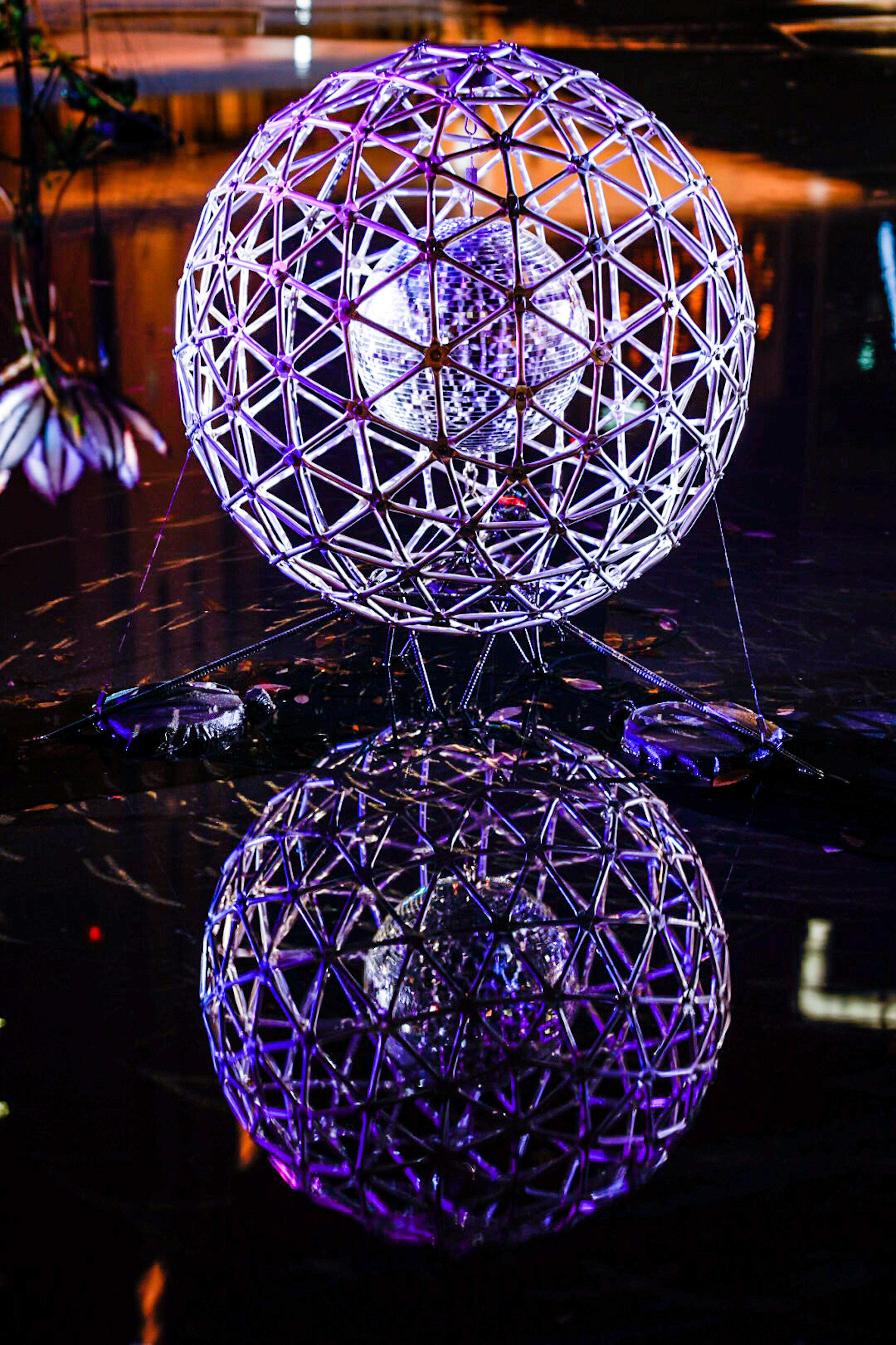 A beautiful geometric sphere sculpture reflected on the water surface