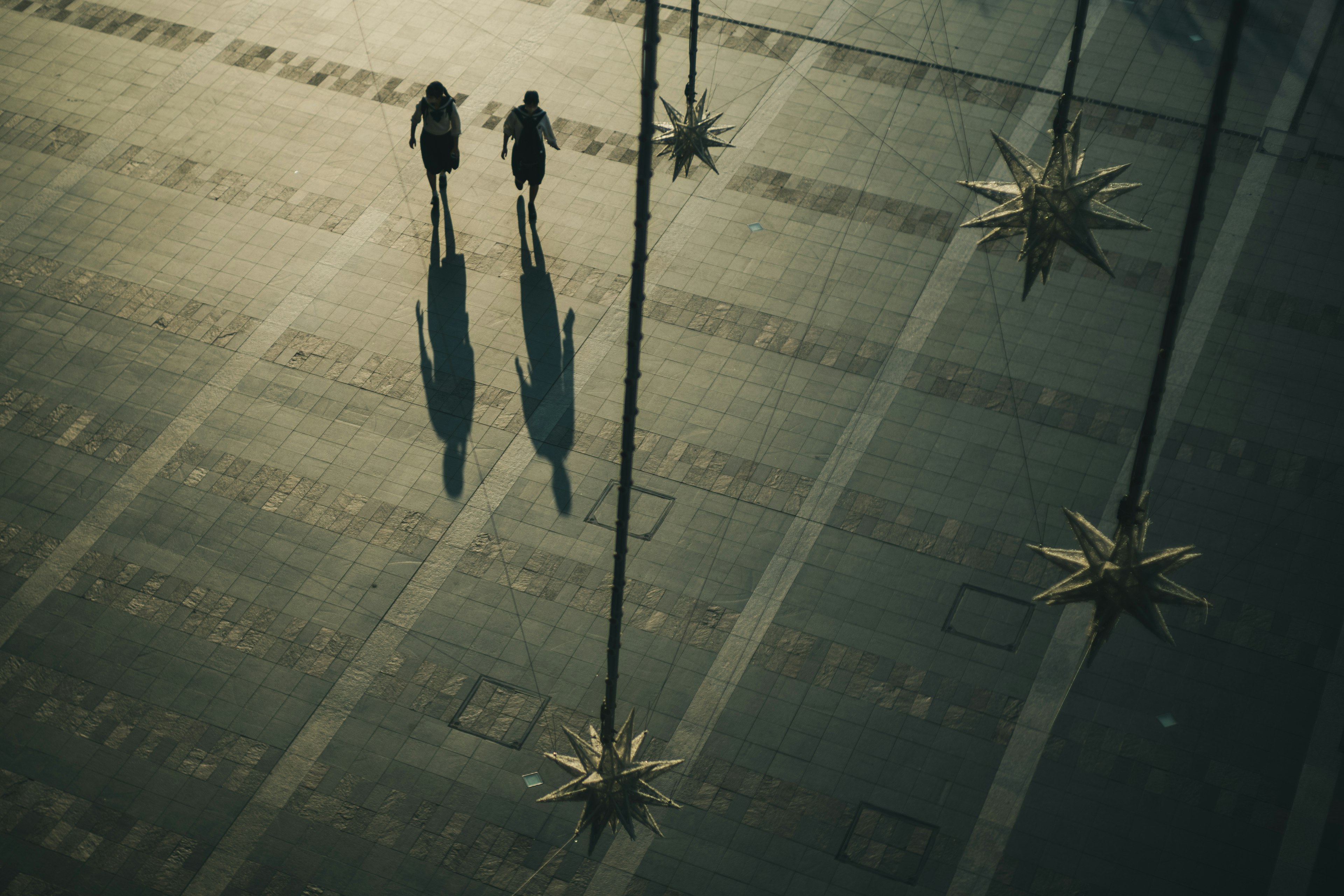 Dos personas caminando y proyectando sombras con objetos en forma de estrella a su alrededor