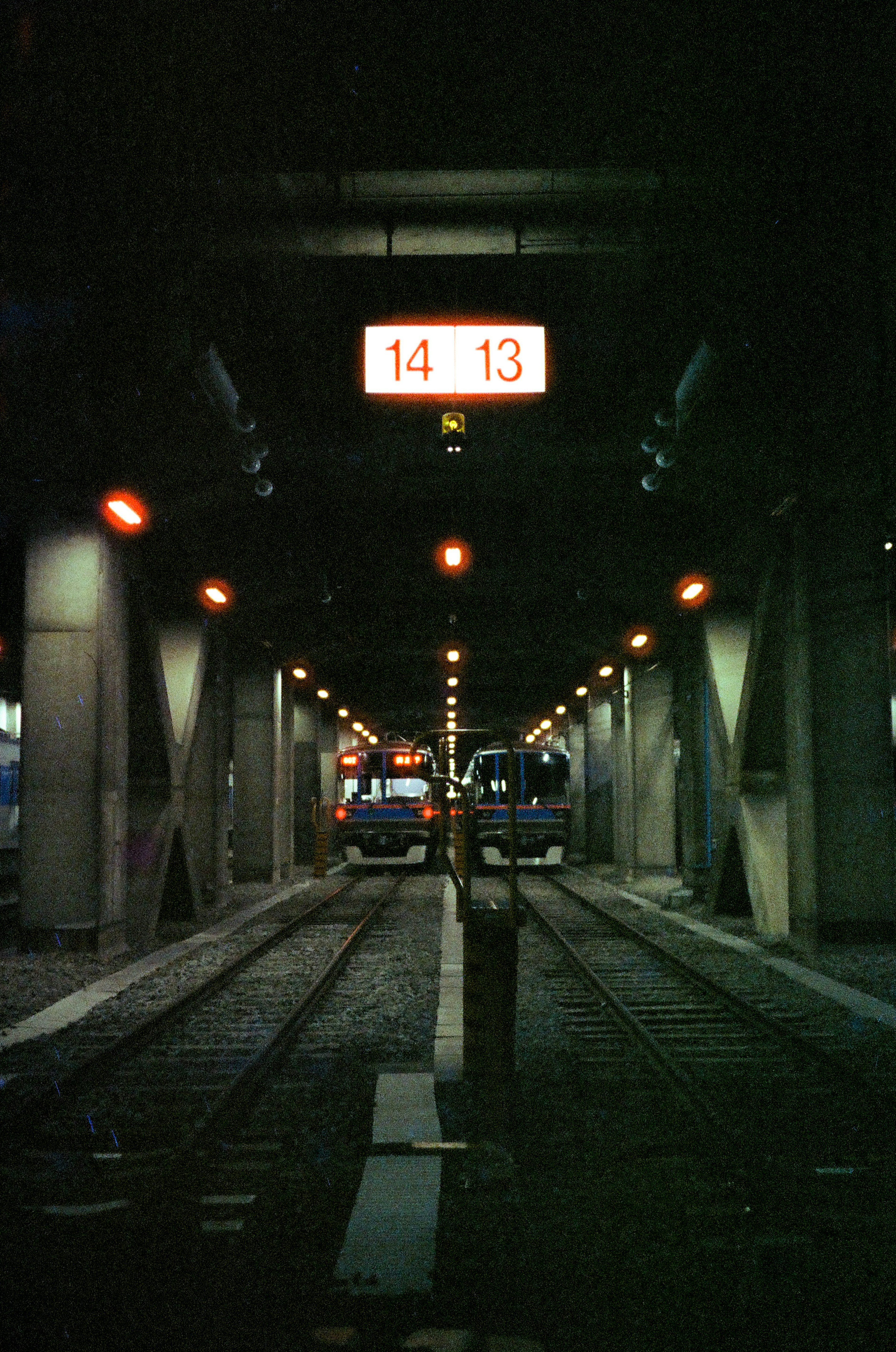 Two trains in a dark tunnel with overhead display board