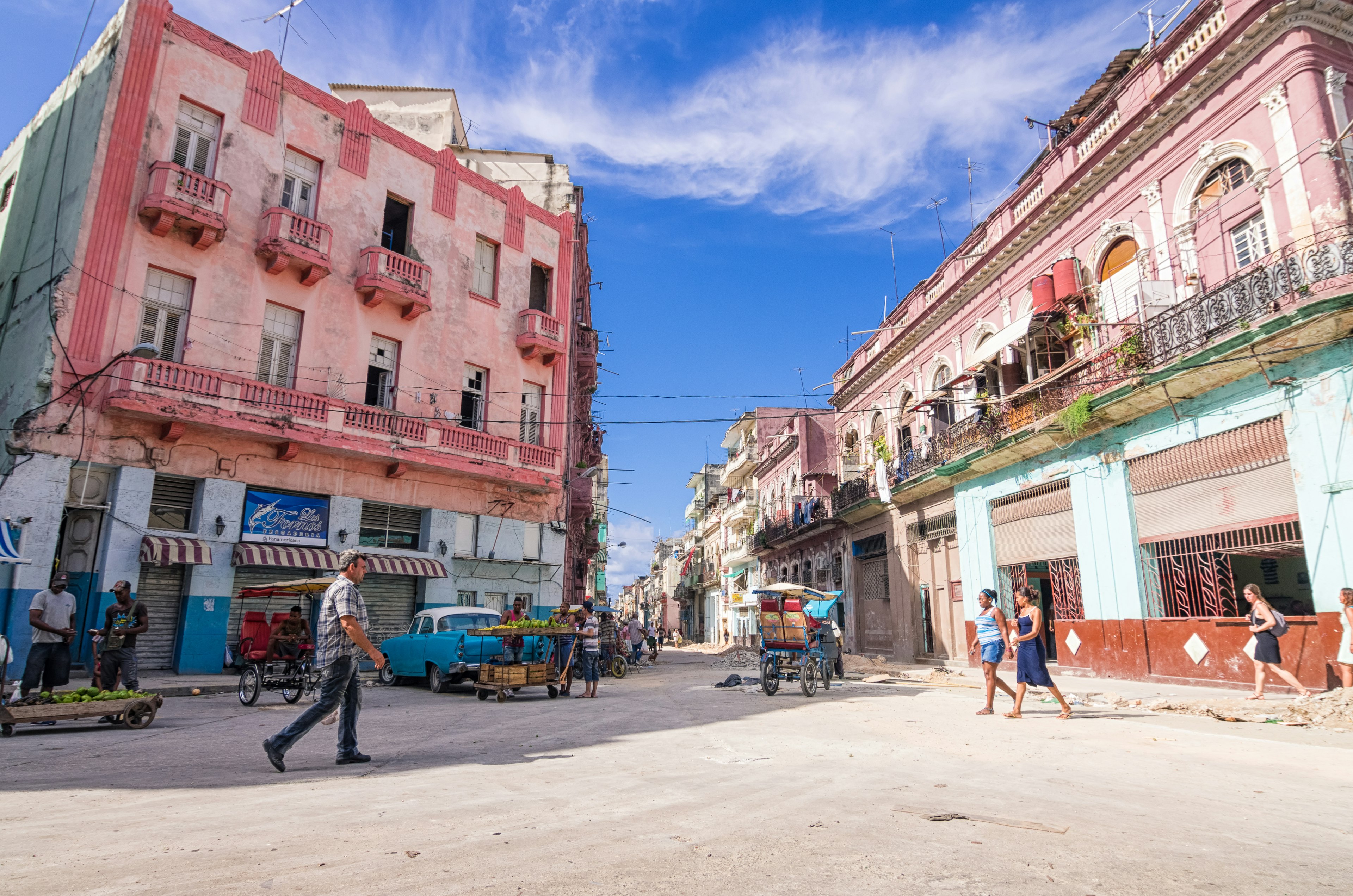 Colorful buildings line a street in Havana with people walking