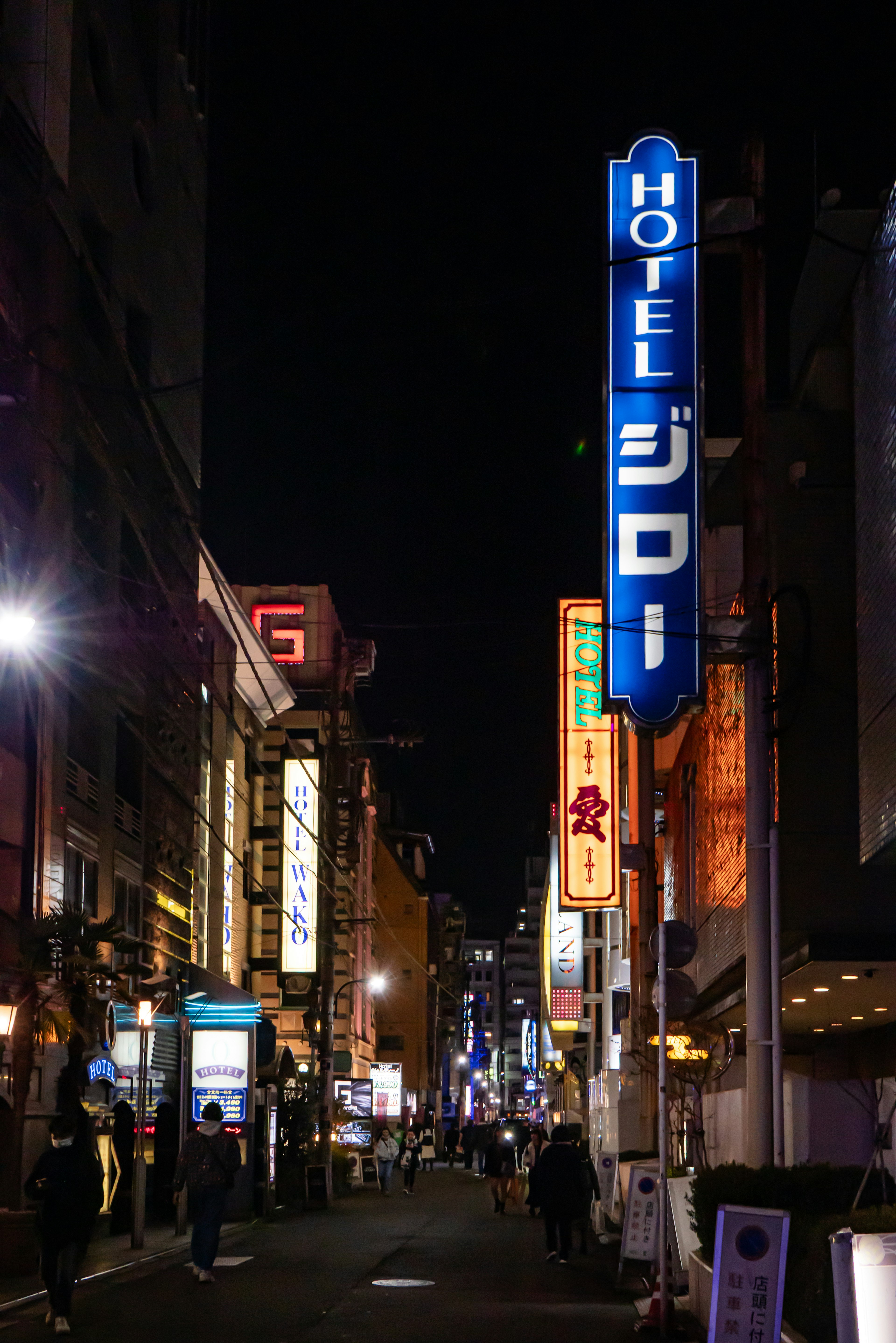 Cartel de neón del Hotel Jiro en una calle bulliciosa por la noche