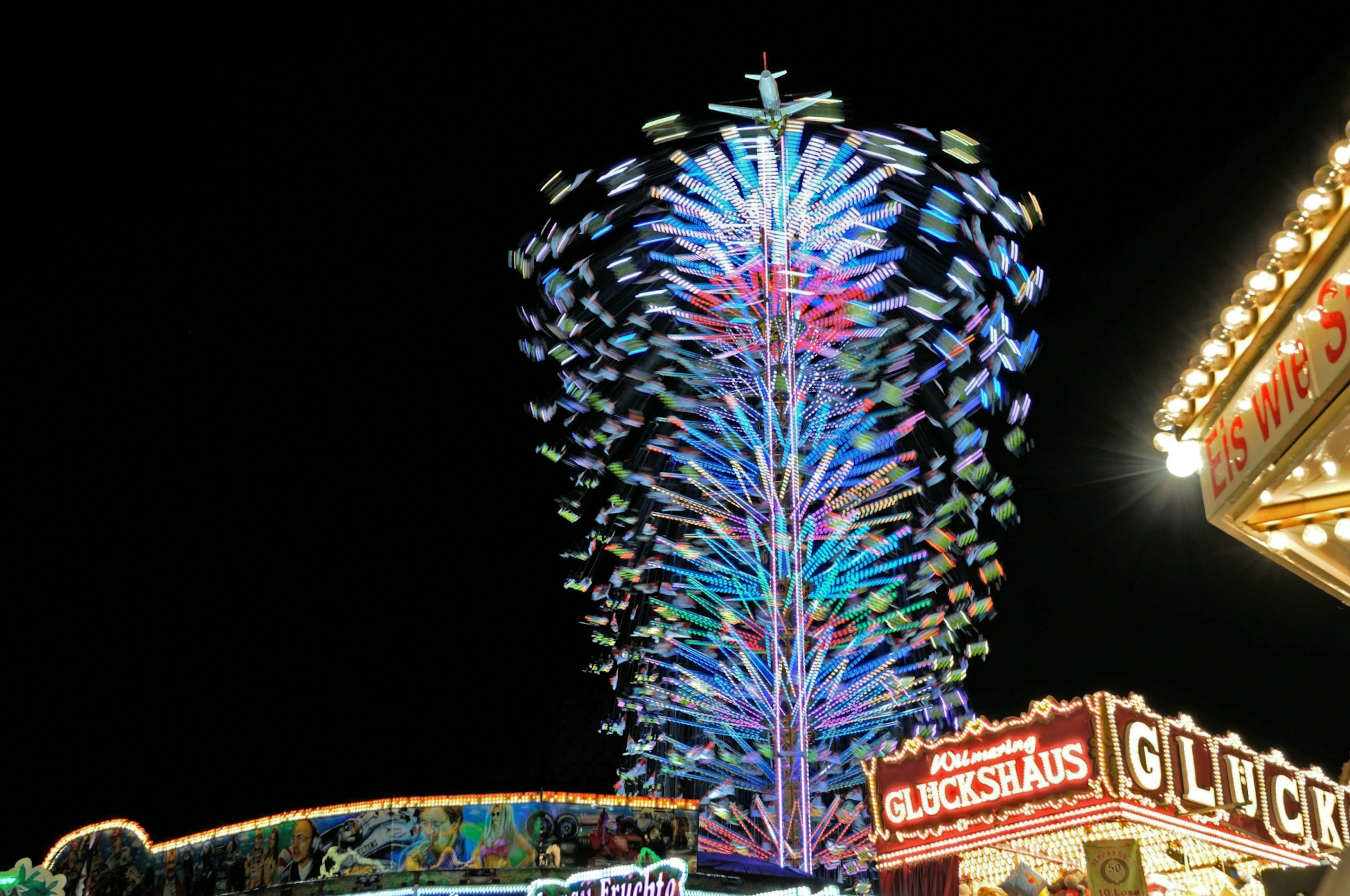 Colorful Ferris wheel illuminated at night with carnival attractions