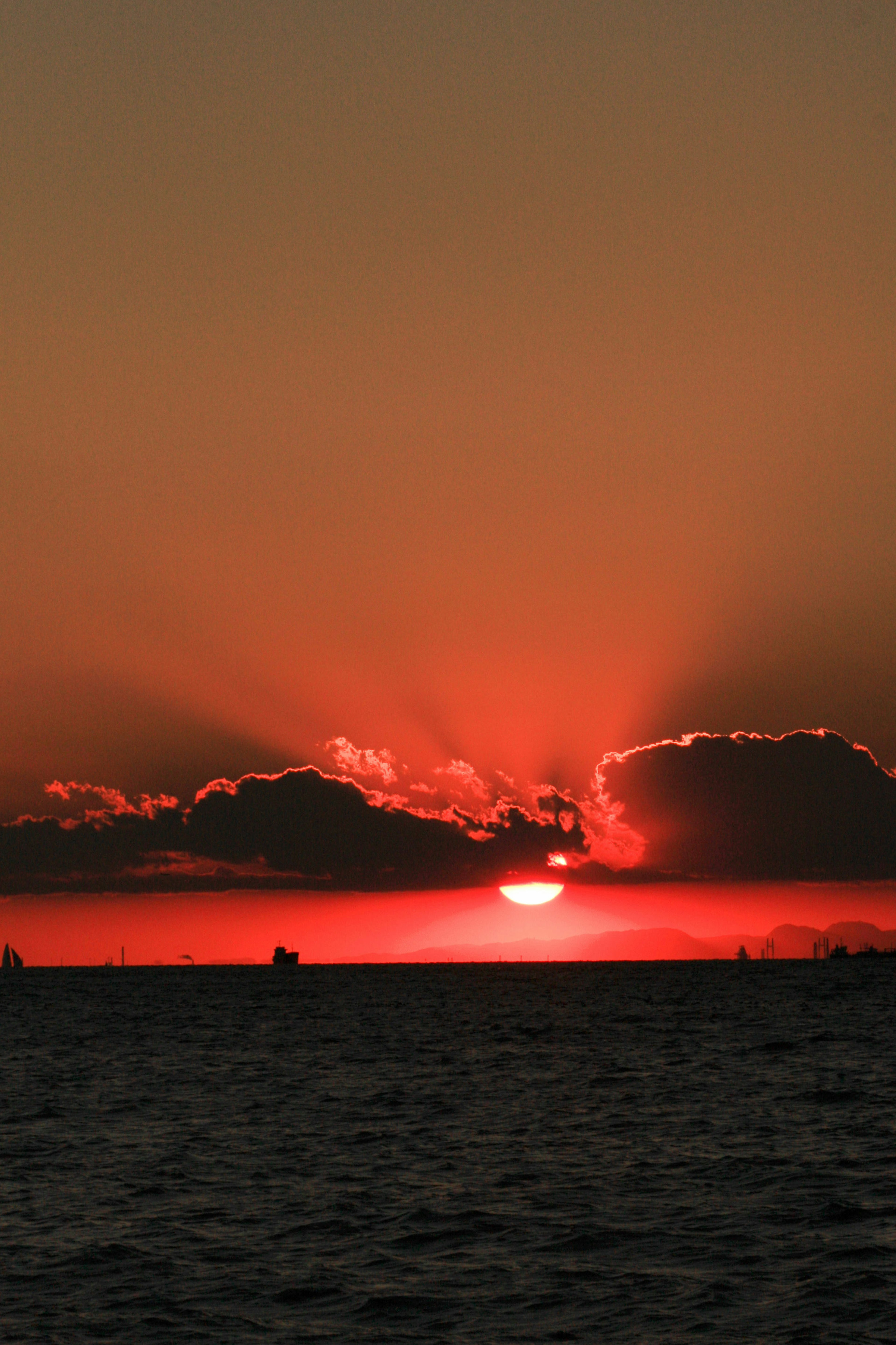 Hermoso atardecer sobre el océano con cielo rojo y siluetas de nubes