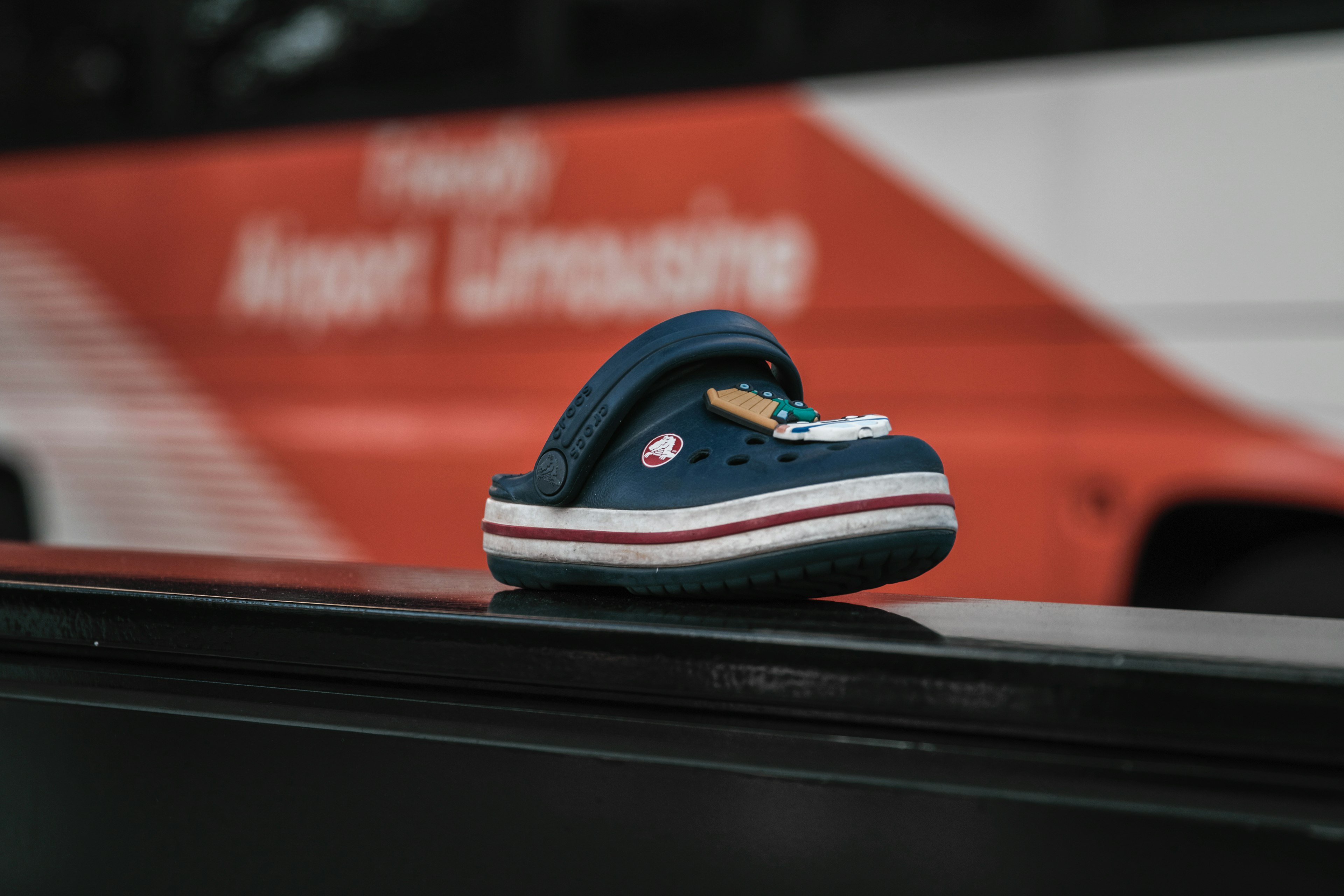 A blue and white striped clog shoe placed on top of a bus