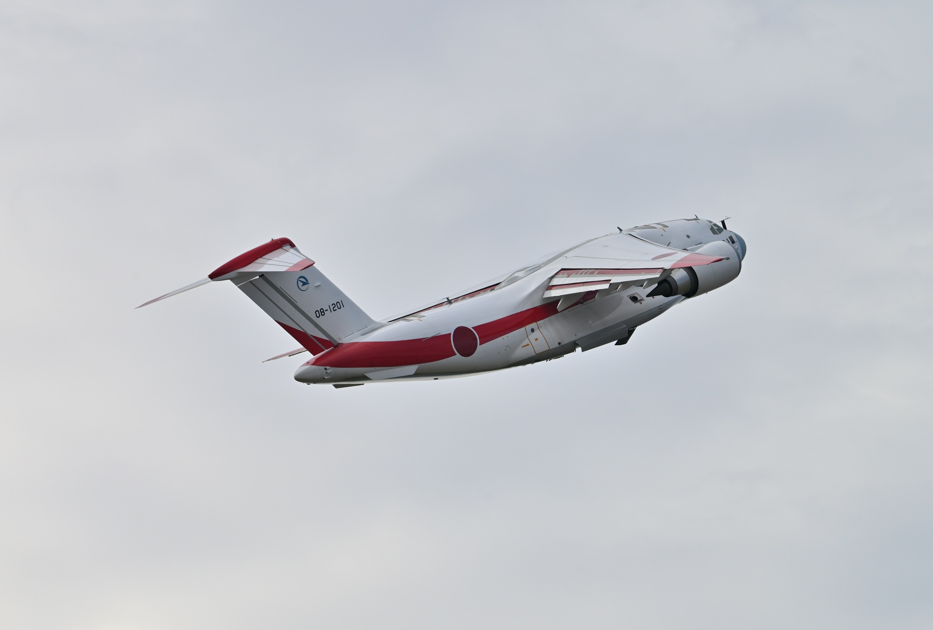 A white and red painted aircraft climbing in the sky