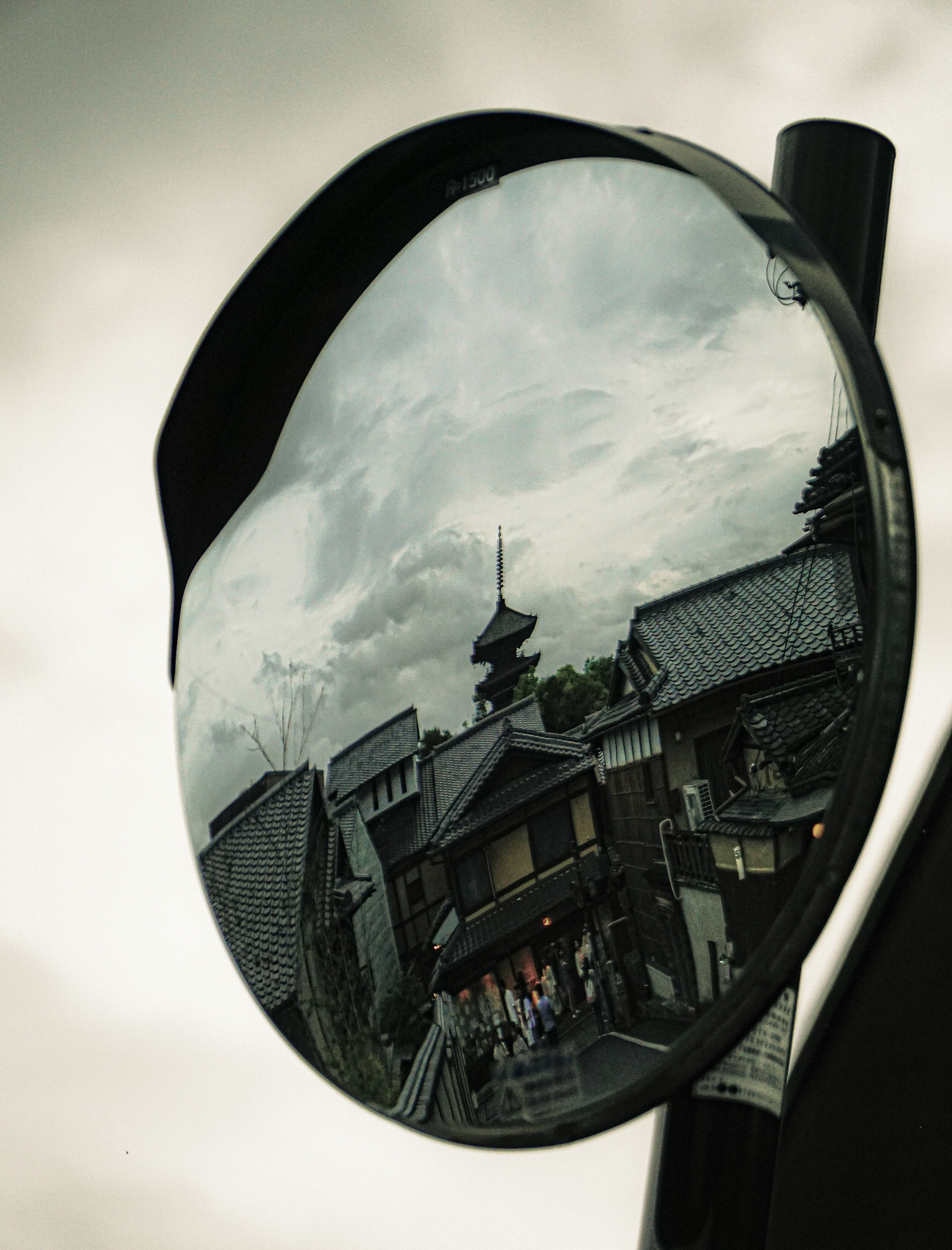 Miroir rond reflétant une scène de rue ancienne et un ciel nuageux