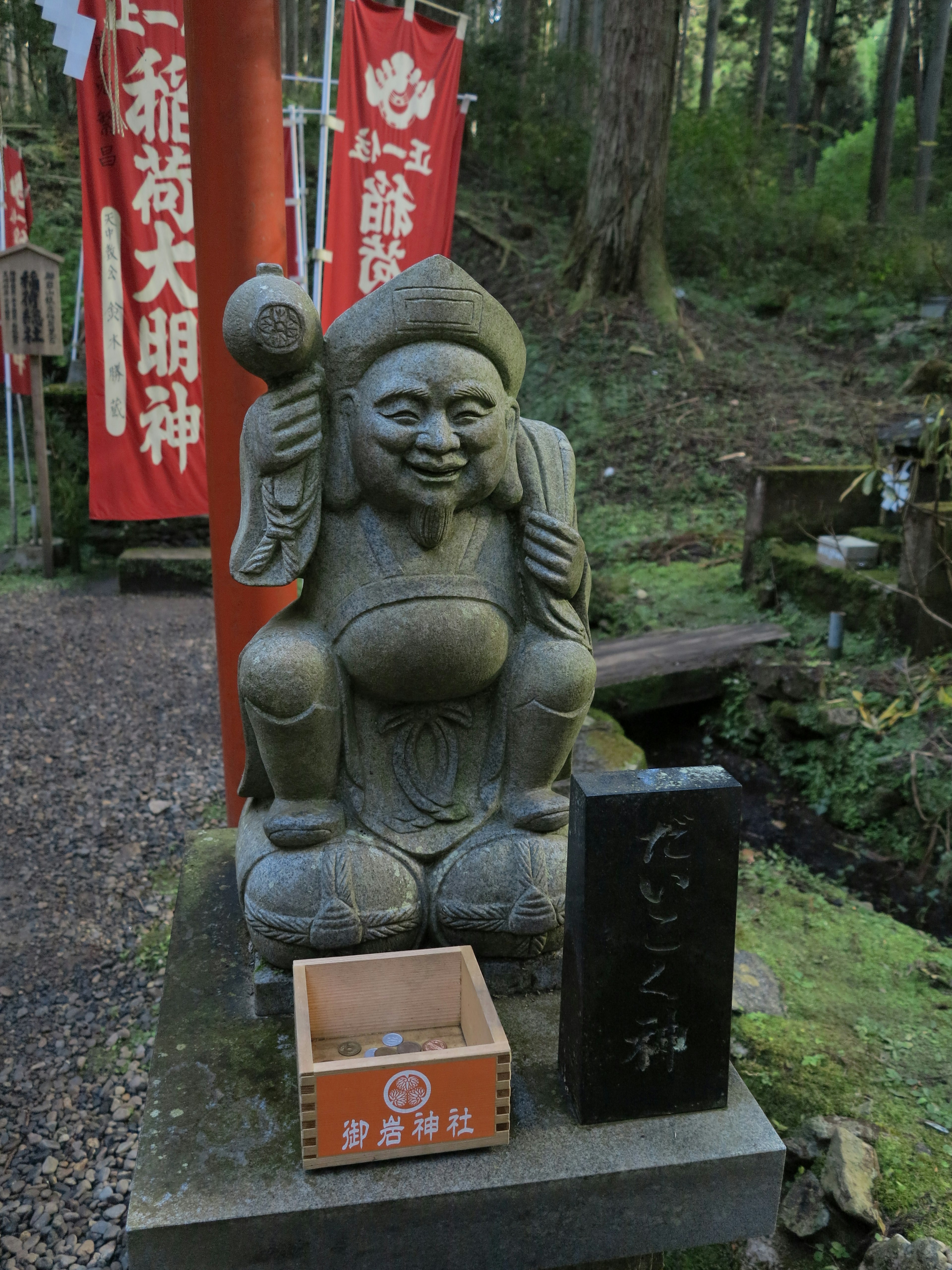 Estatua de piedra de una deidad sentada en un entorno de santuario en el bosque