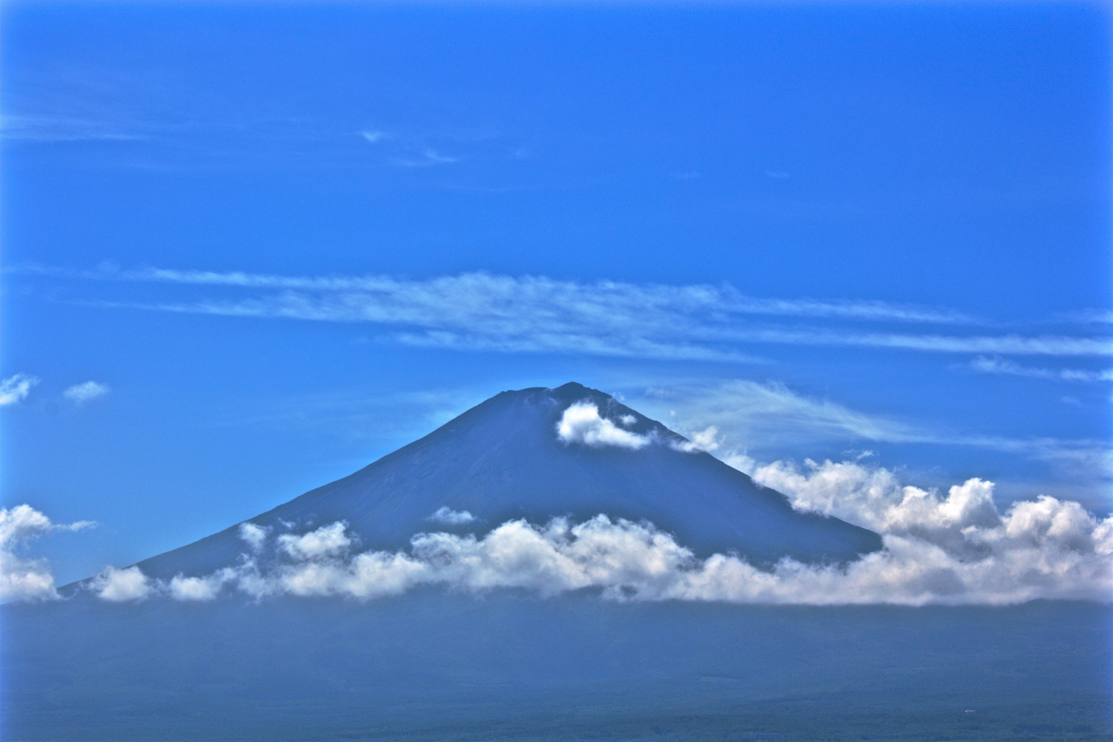 ทิวทัศน์ที่สวยงามของภูเขาฟูจิที่ล้อมรอบด้วยท้องฟ้าสีฟ้าและเมฆ