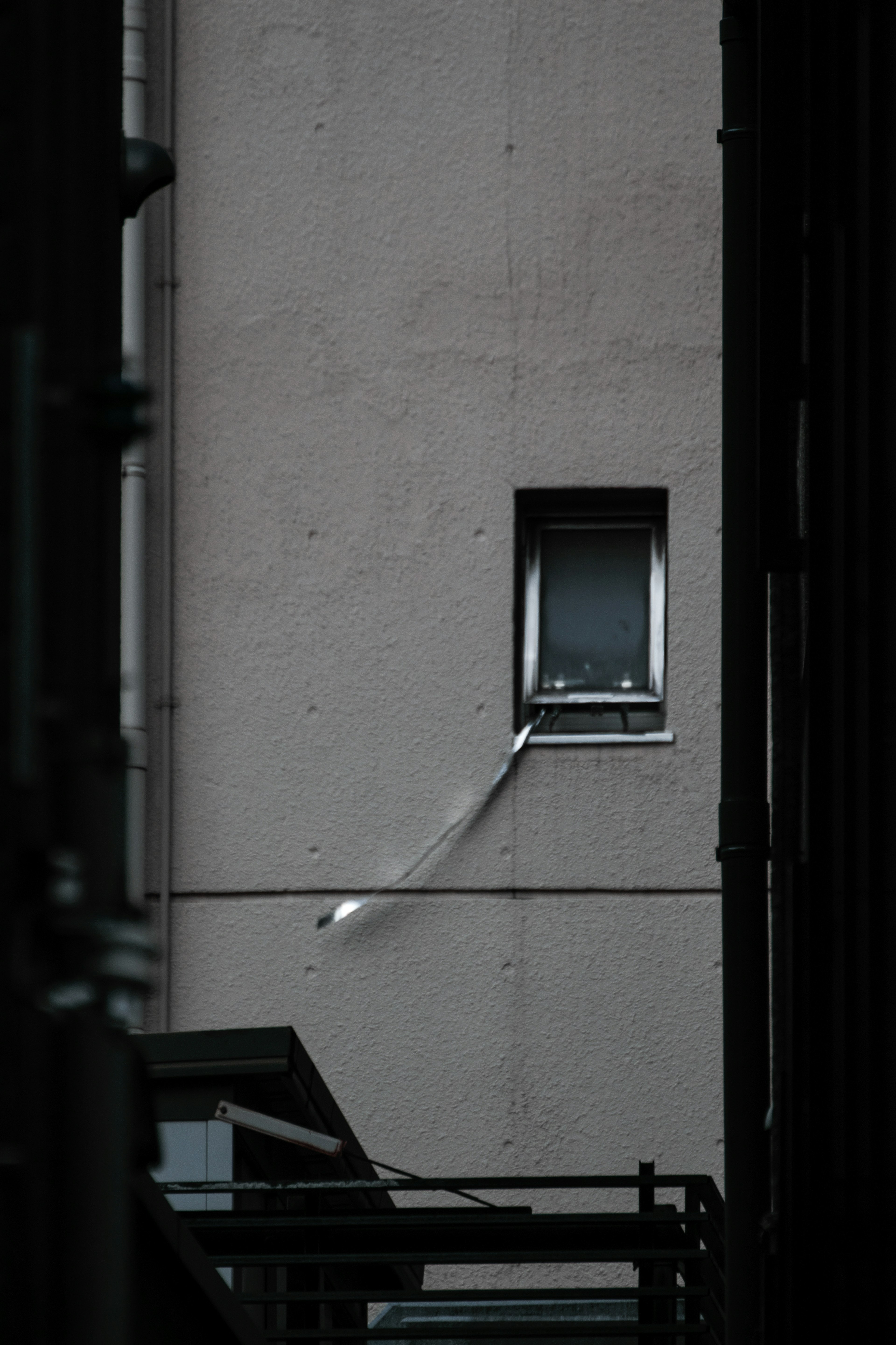 Fenêtre sur un mur en béton entourée de structures sombres