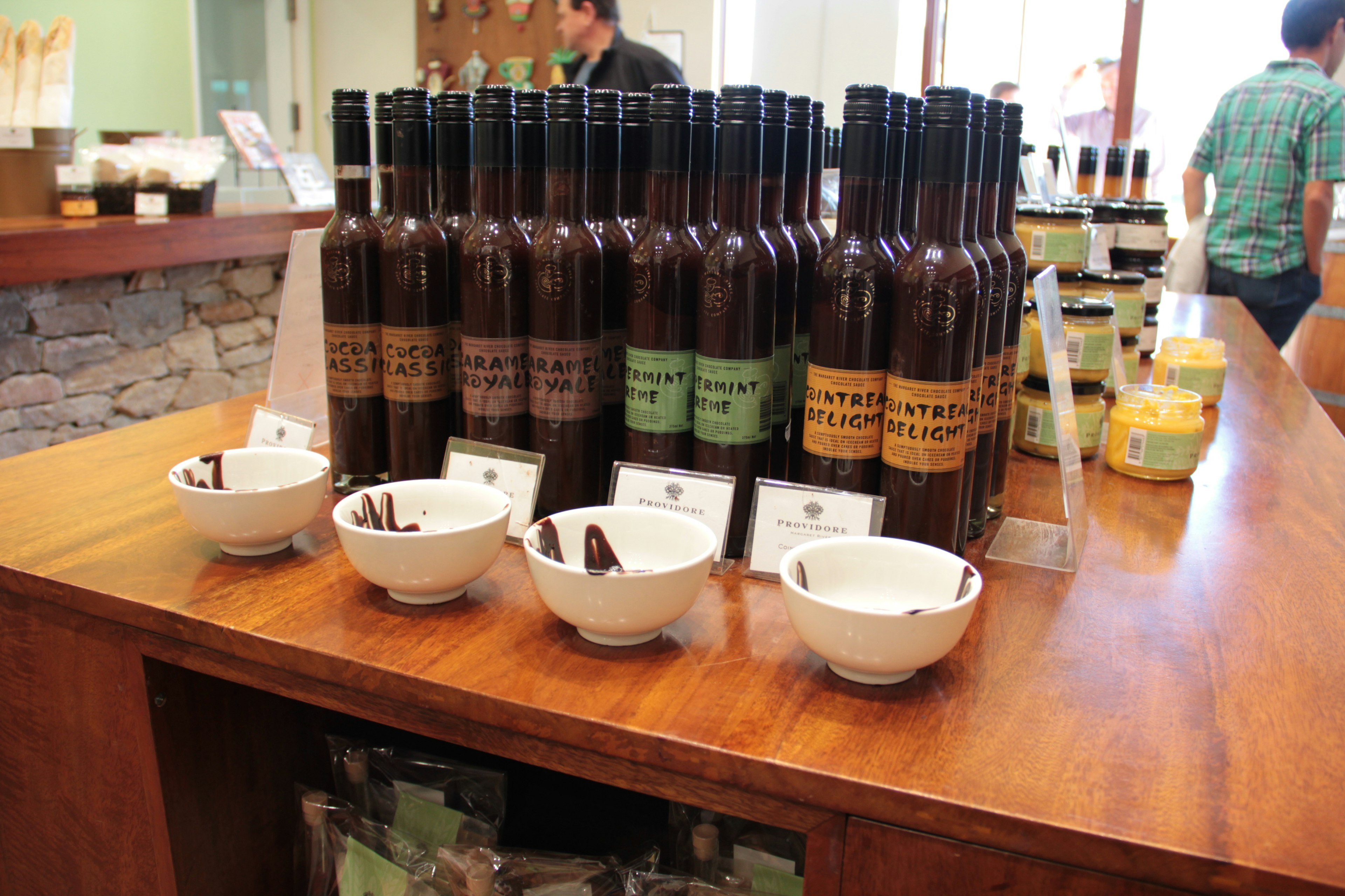 Bouteilles d'huile d'olive exposées sur une table en bois avec des bols de dégustation