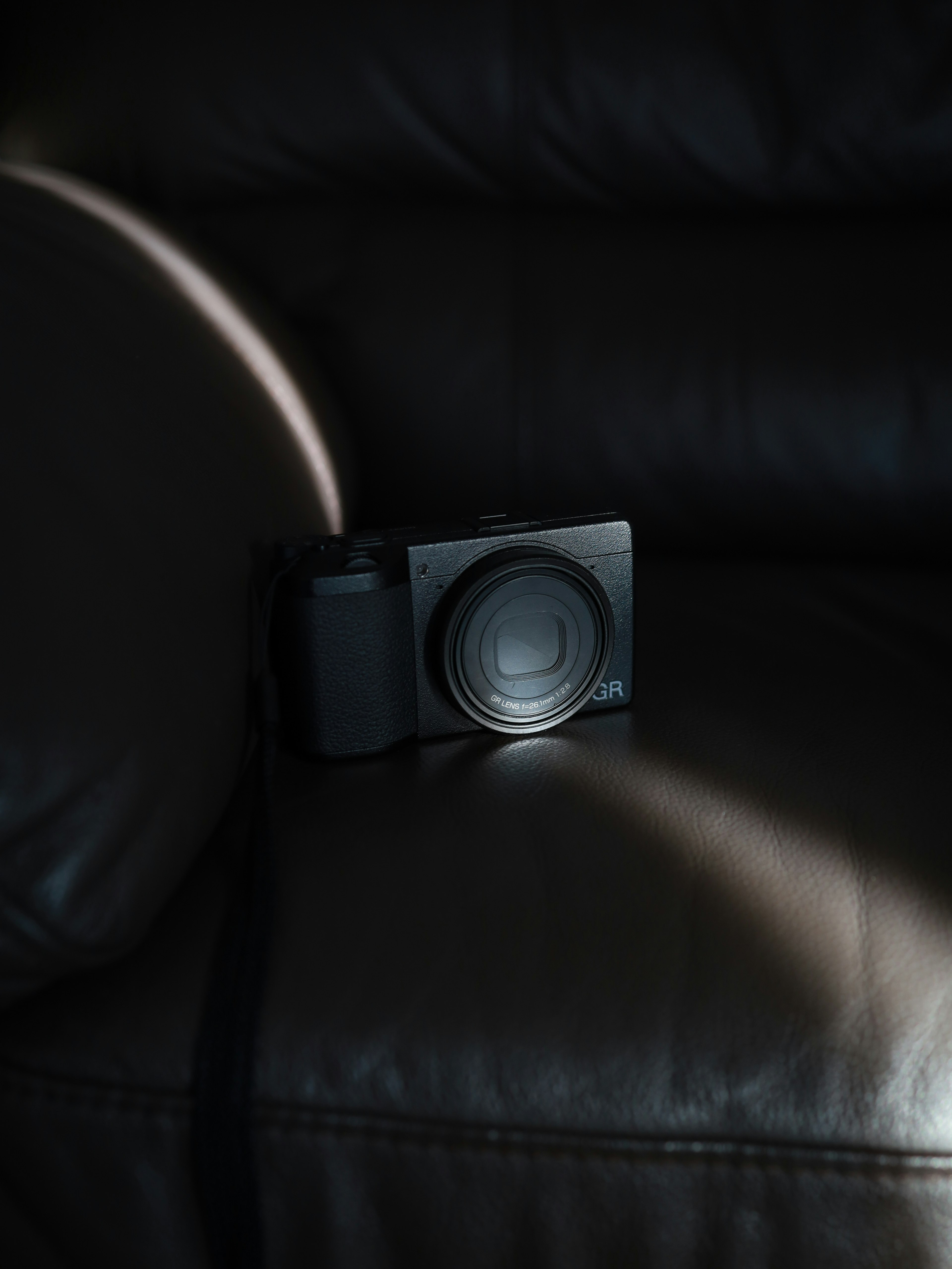 Black camera resting on a brown leather couch