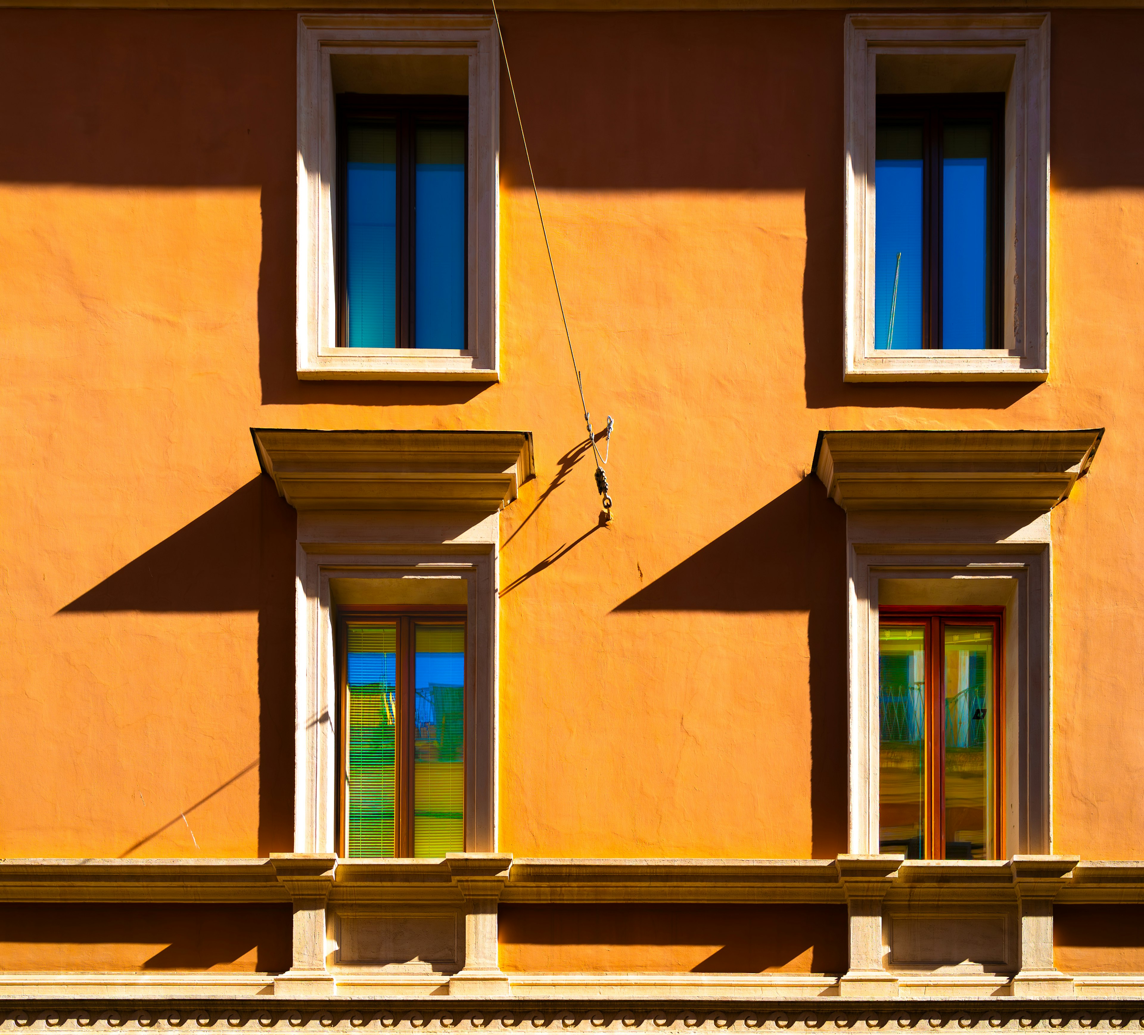 Außenansicht eines Gebäudes mit orangefarbener Wand und vier Fenstern