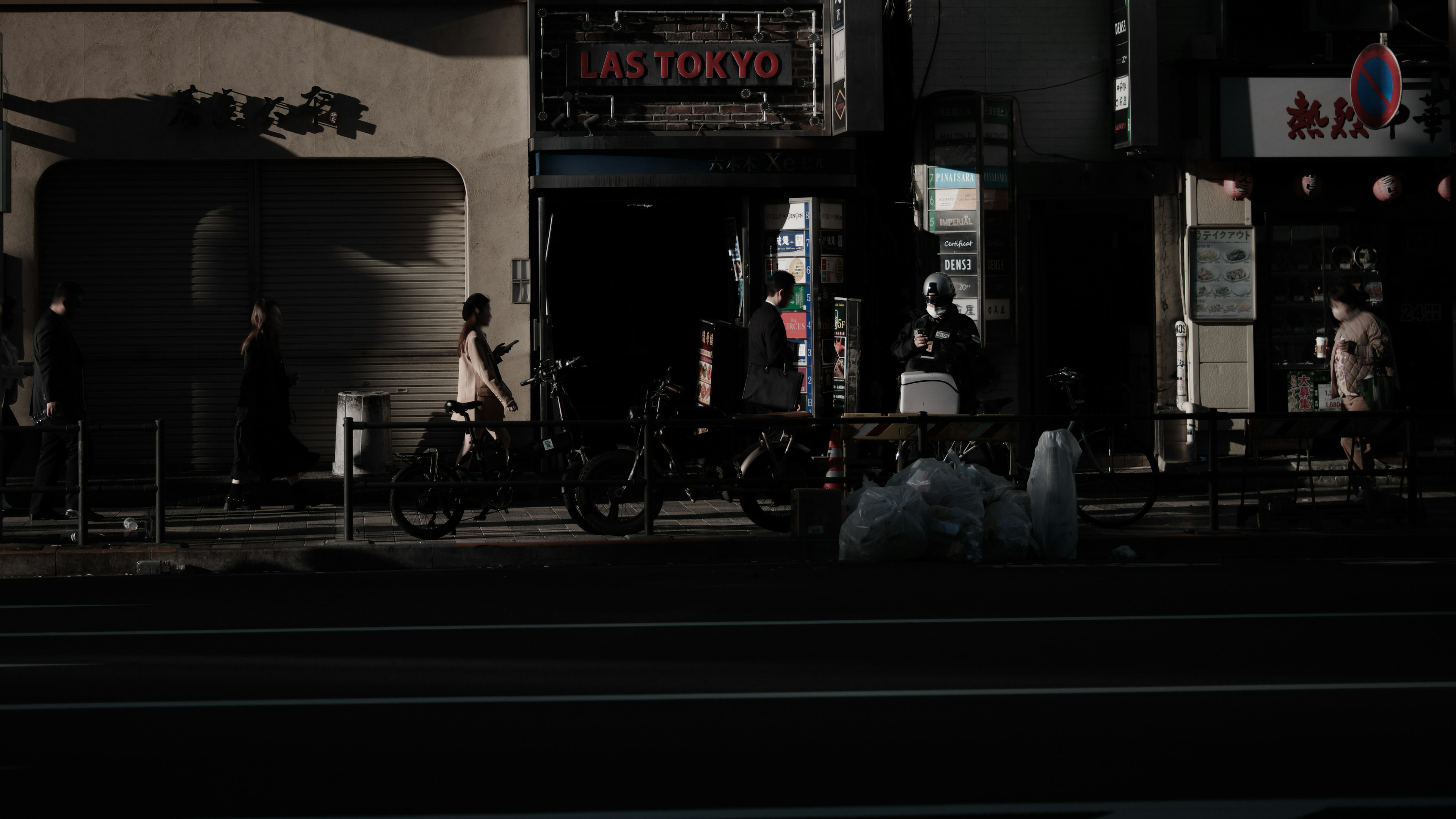 暗い通りの風景に人々と自転車が見える