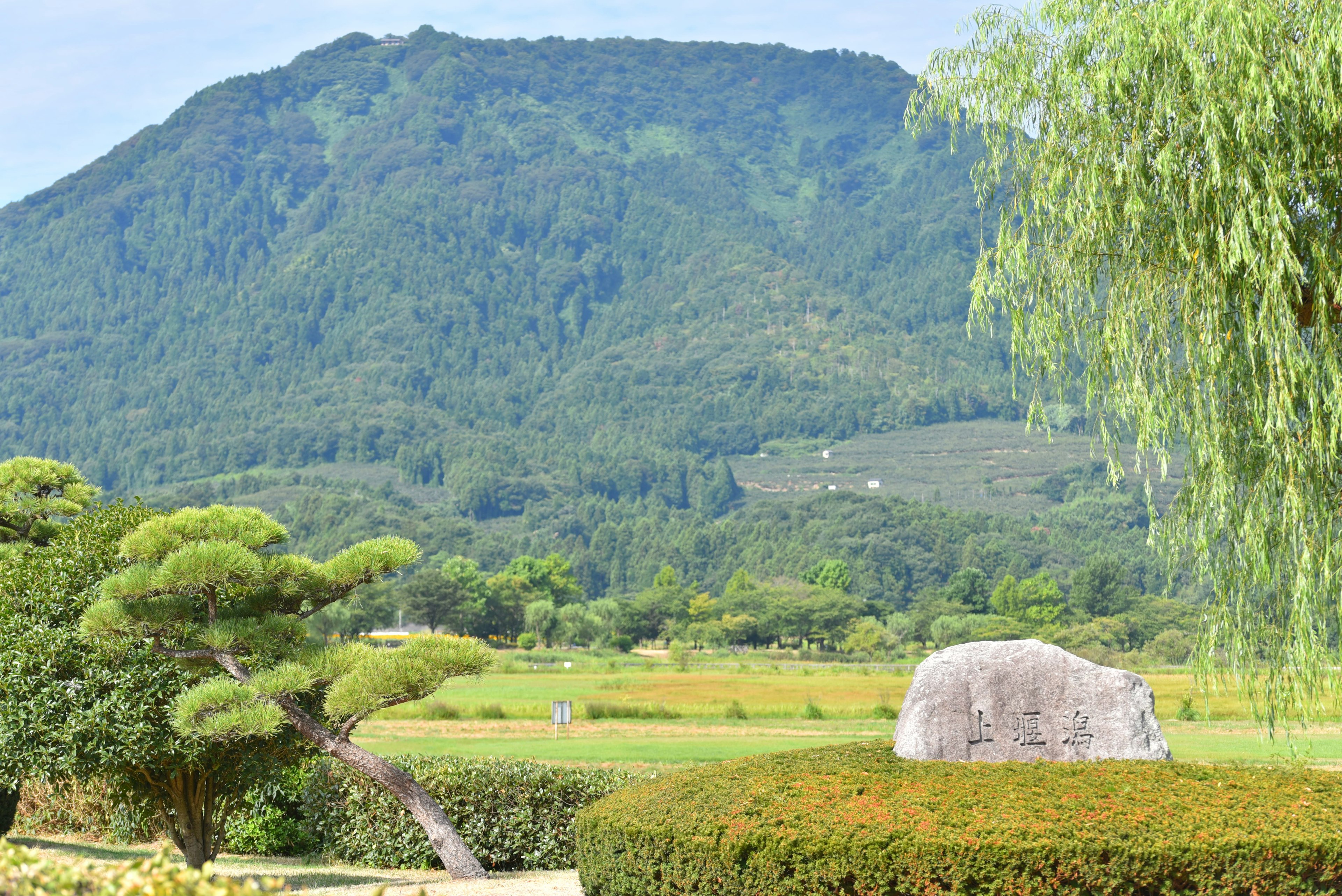 緑豊かな山と田園風景を背景にした石と庭の景観