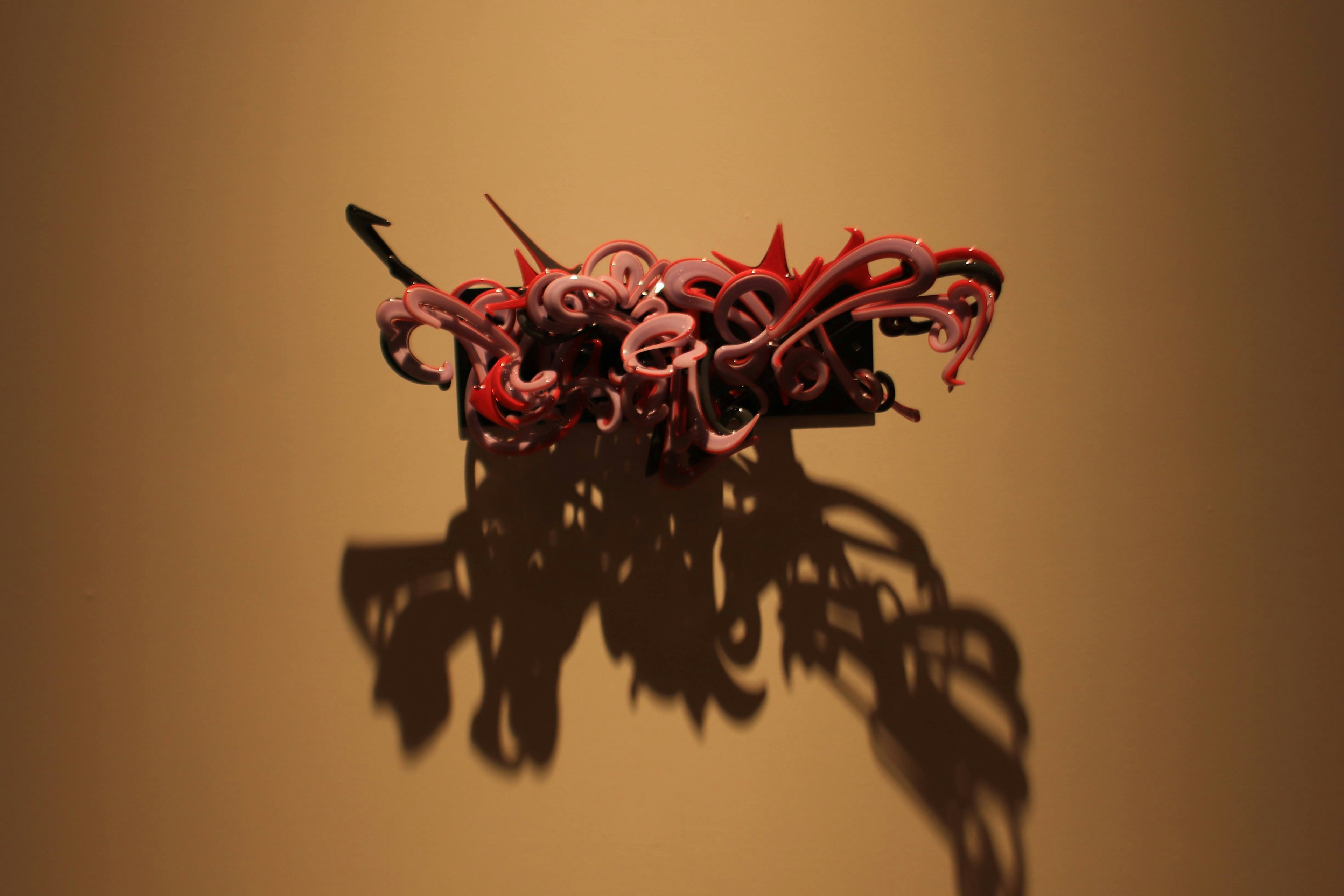 Abstract red tentacle sculpture mounted on a wall