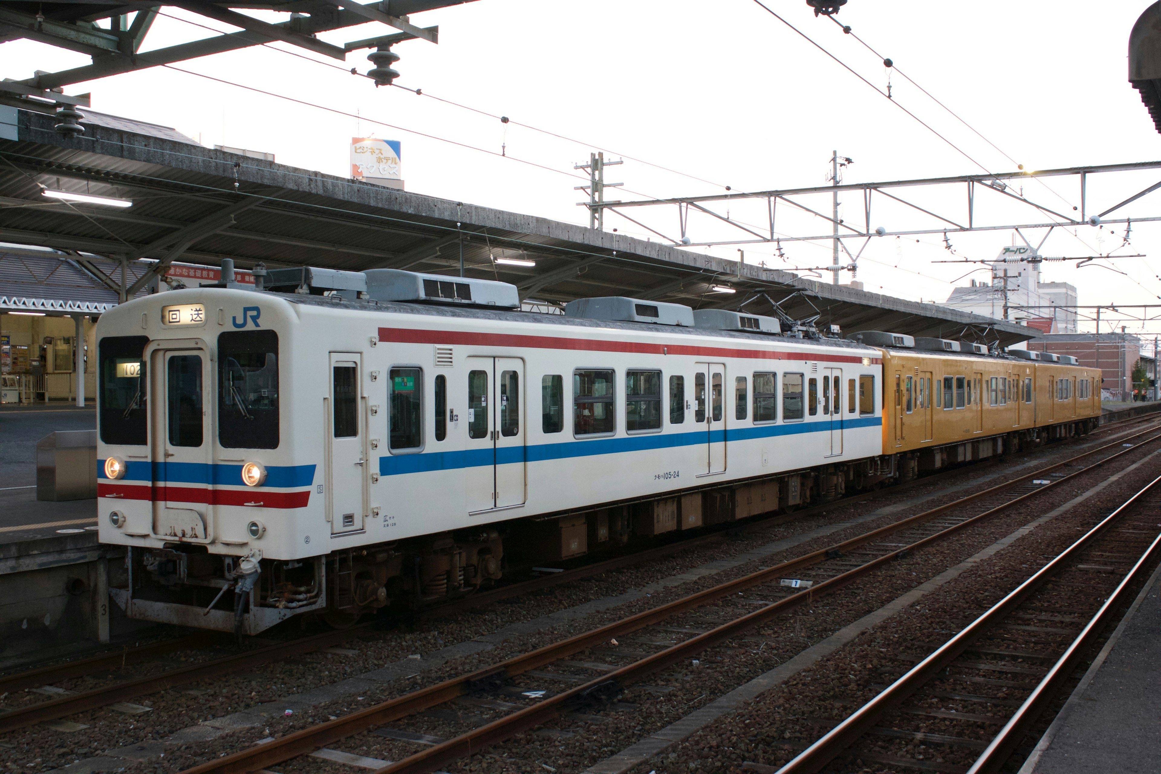 駅に停車中の白と青の電車と黄色の電車