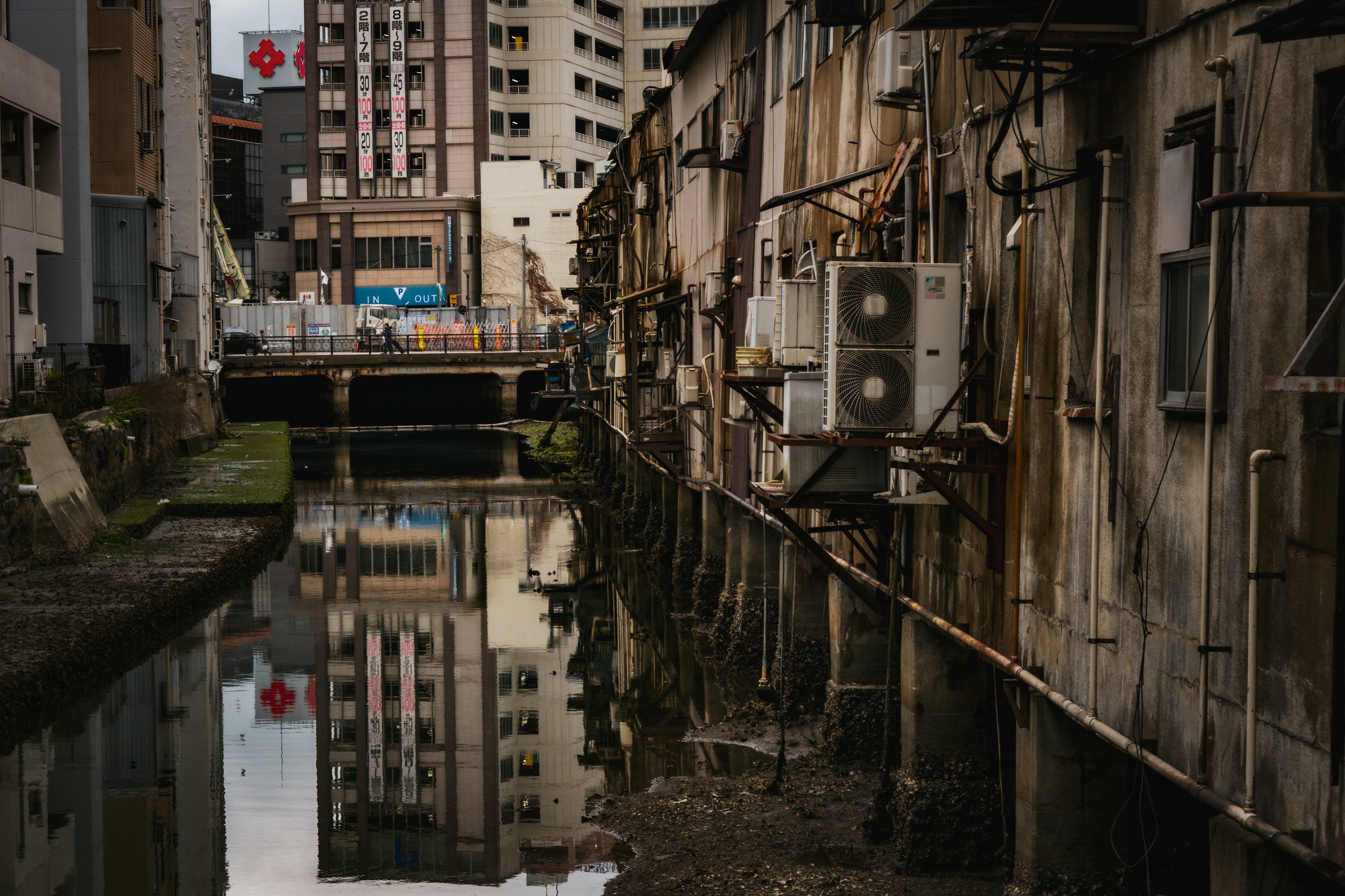 古い建物が並ぶ狭い水路の風景 電気機器が取り付けられた外壁の反射