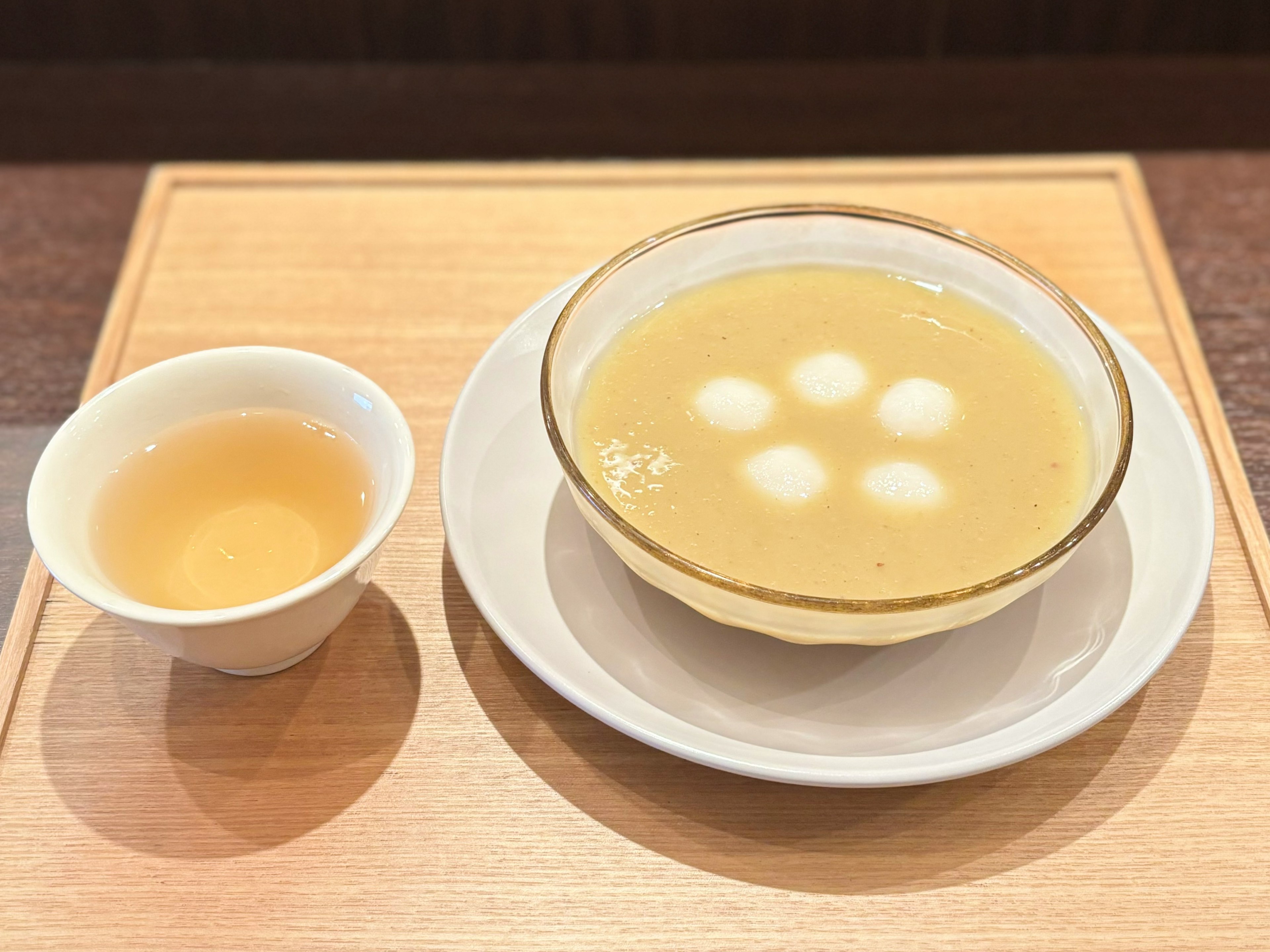 Bowl of sweet soup with glutinous rice balls and a cup of tea