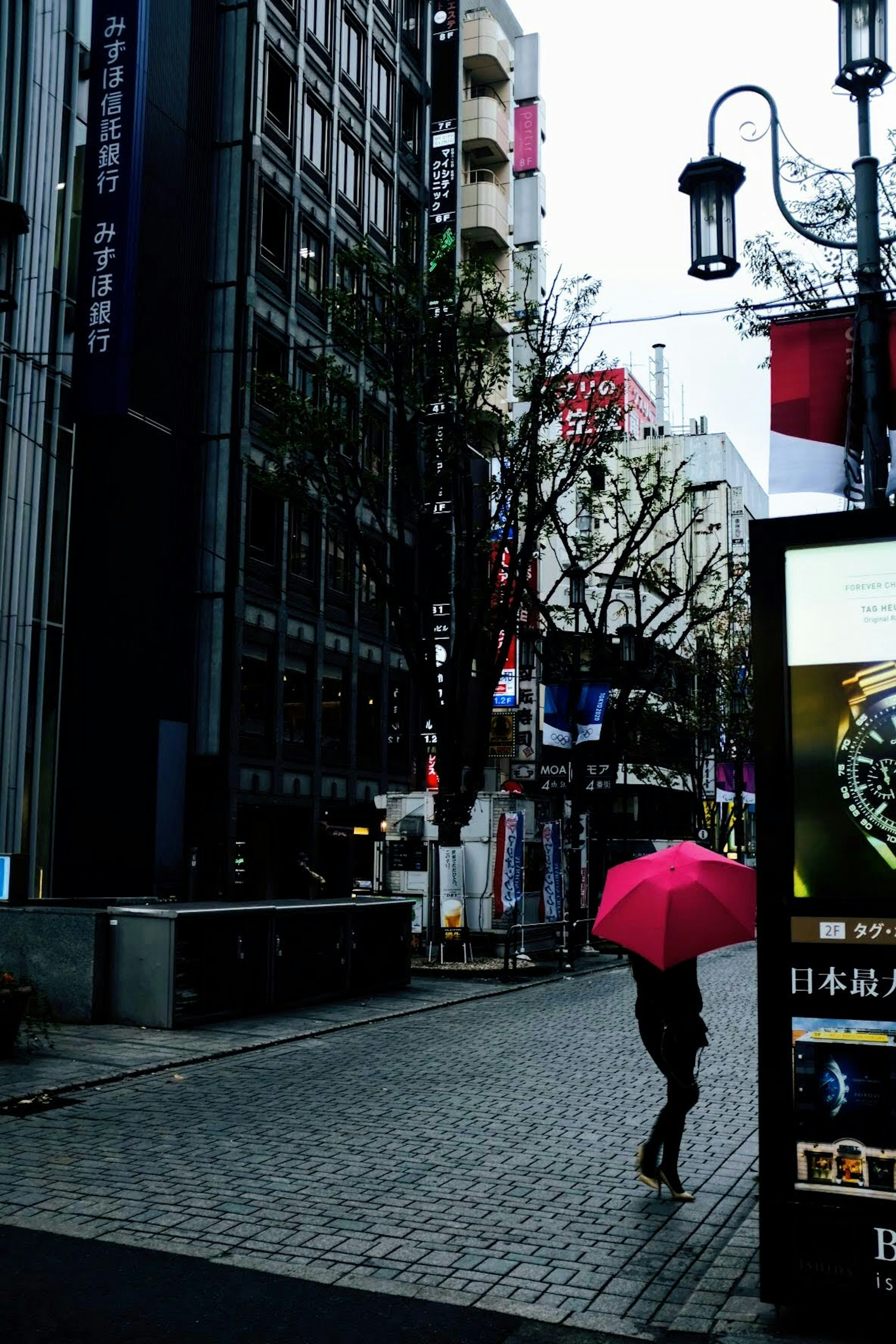 雨の中、ピンクの傘を持った人が歩いている都市の風景