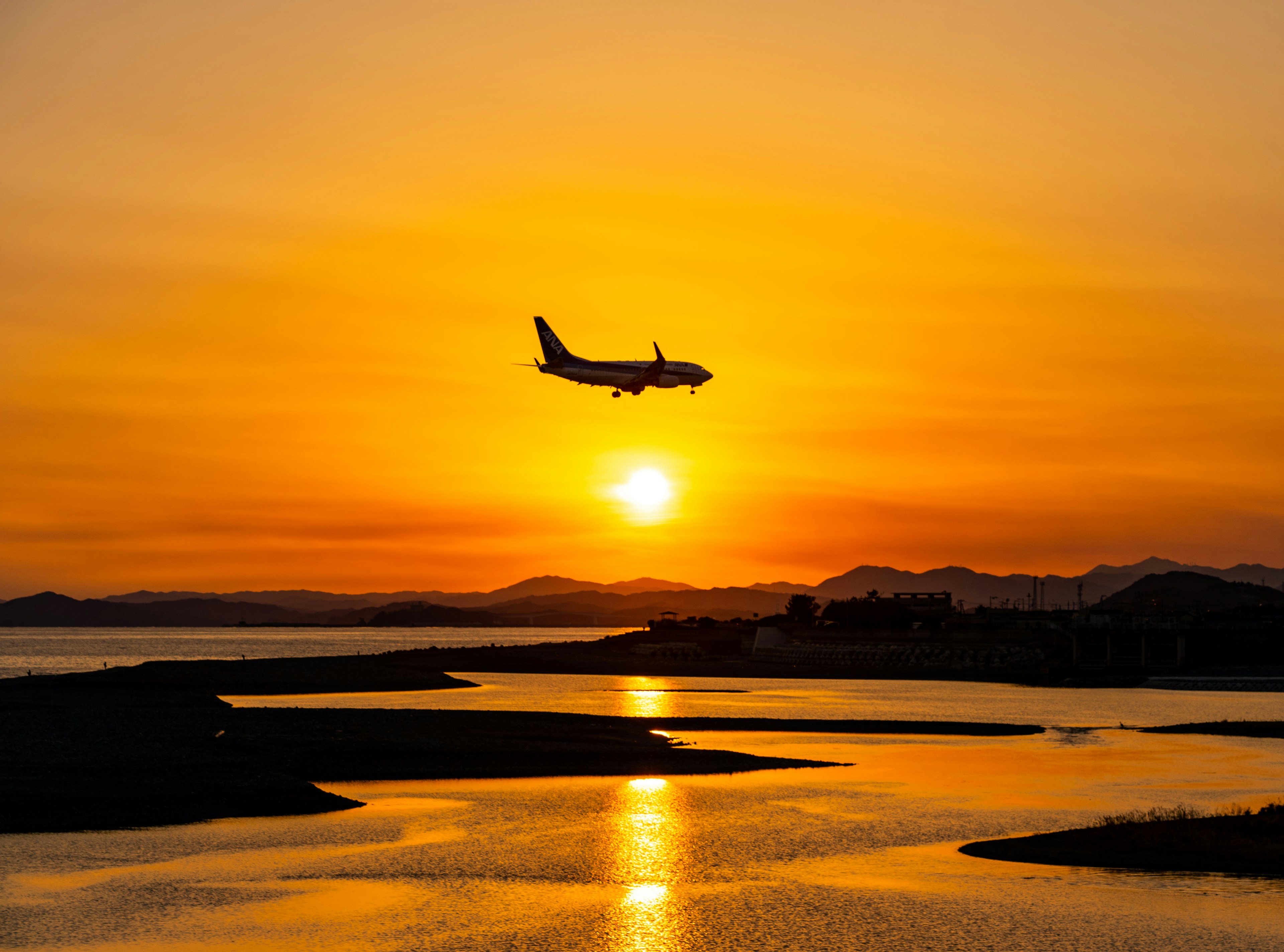 夕日を背景に飛行機が着陸している風景